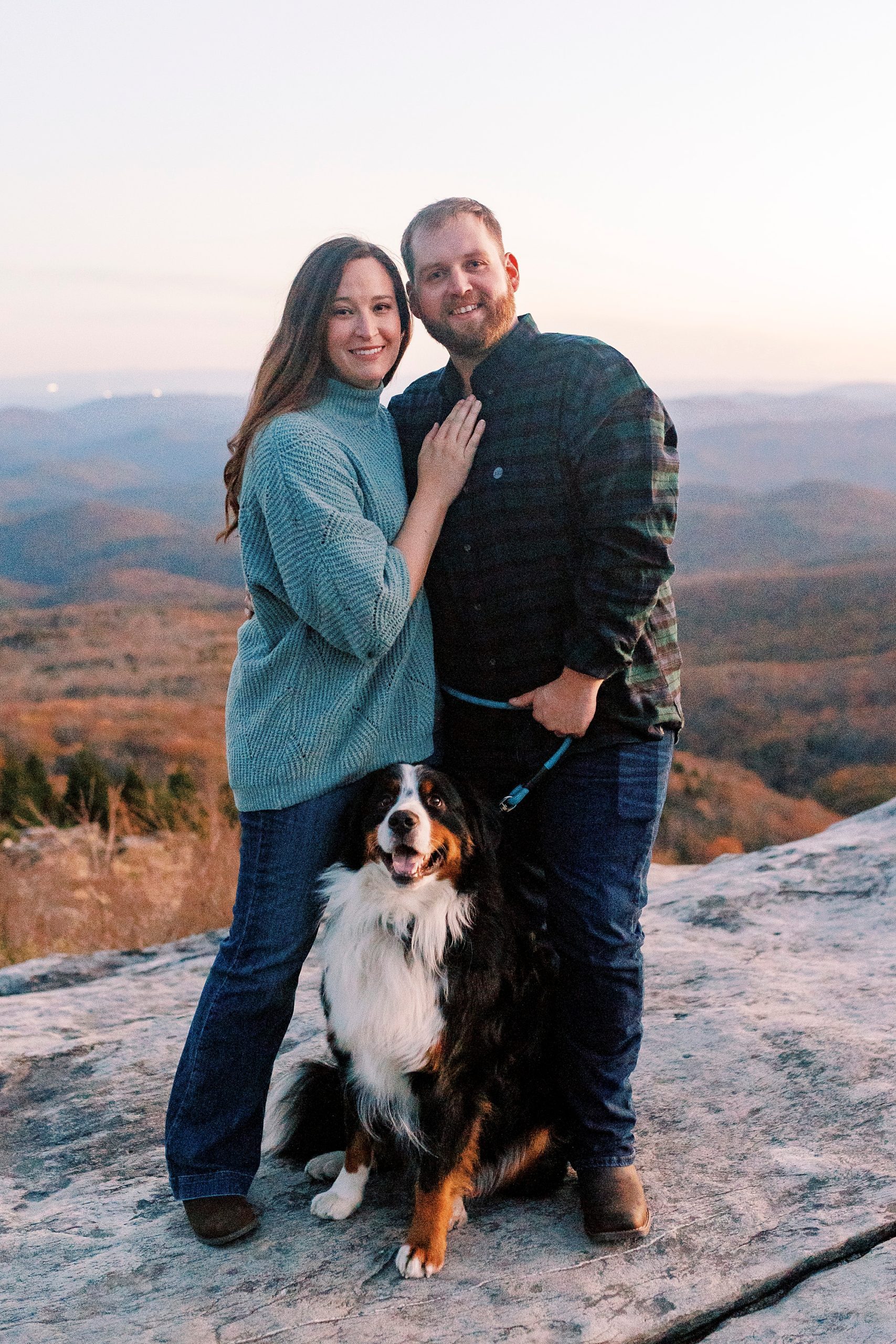 engaged couple poses with Bernese Mountain Dog during Rough Ridge in the Blue Ridge Parkway engagement session