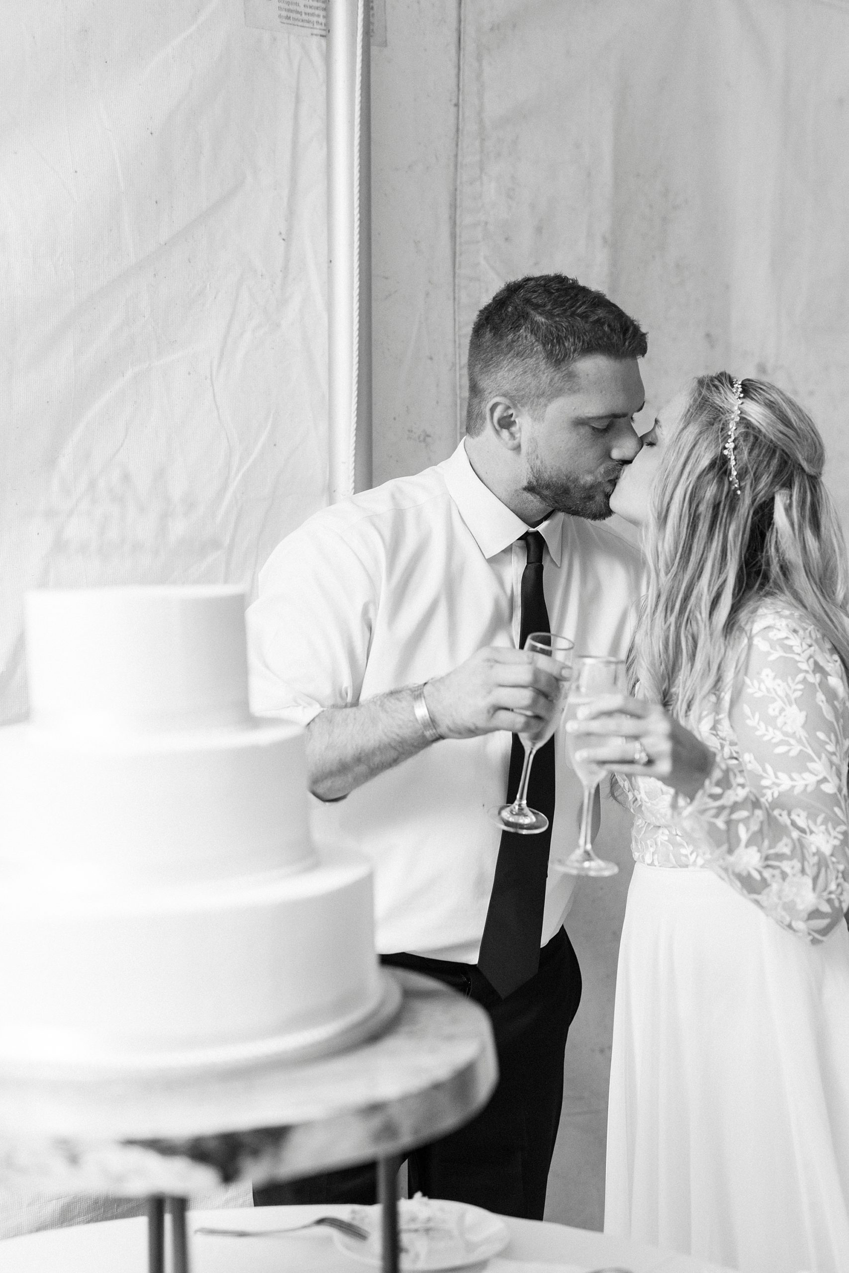 bride and groom kiss by wedding cake during Blowing Rock NC wedding reception