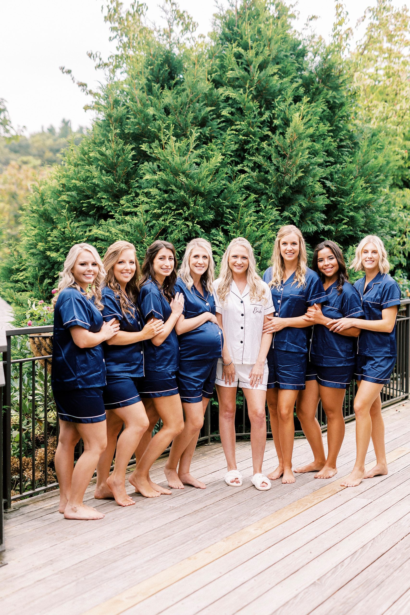 bride and bridesmaids pose on balcony in matching pajamas
