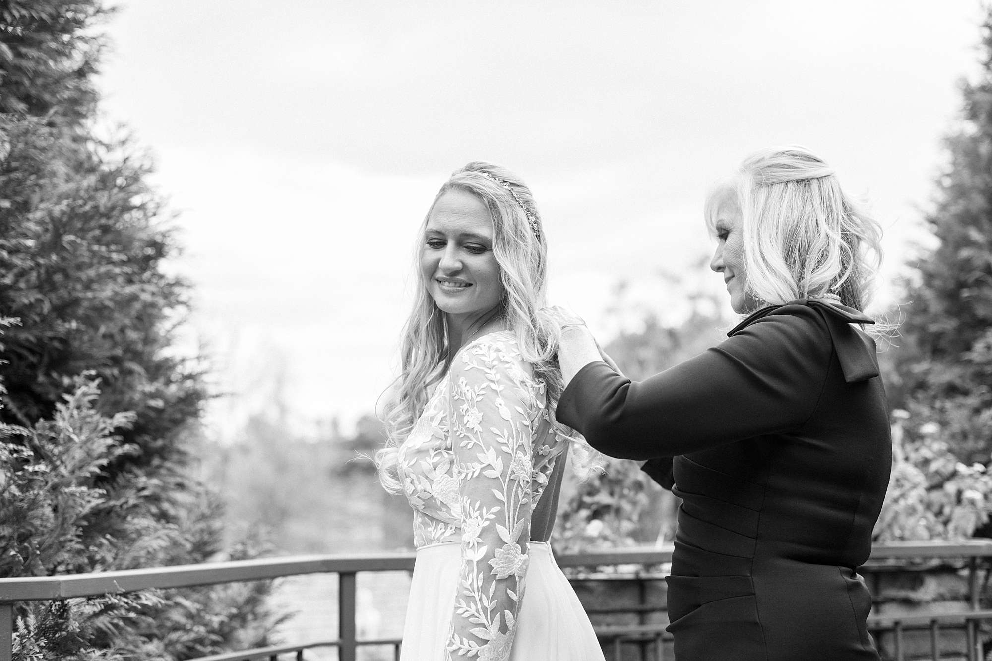 mother helps bride with wedding dress on balcony at Chetola Resort