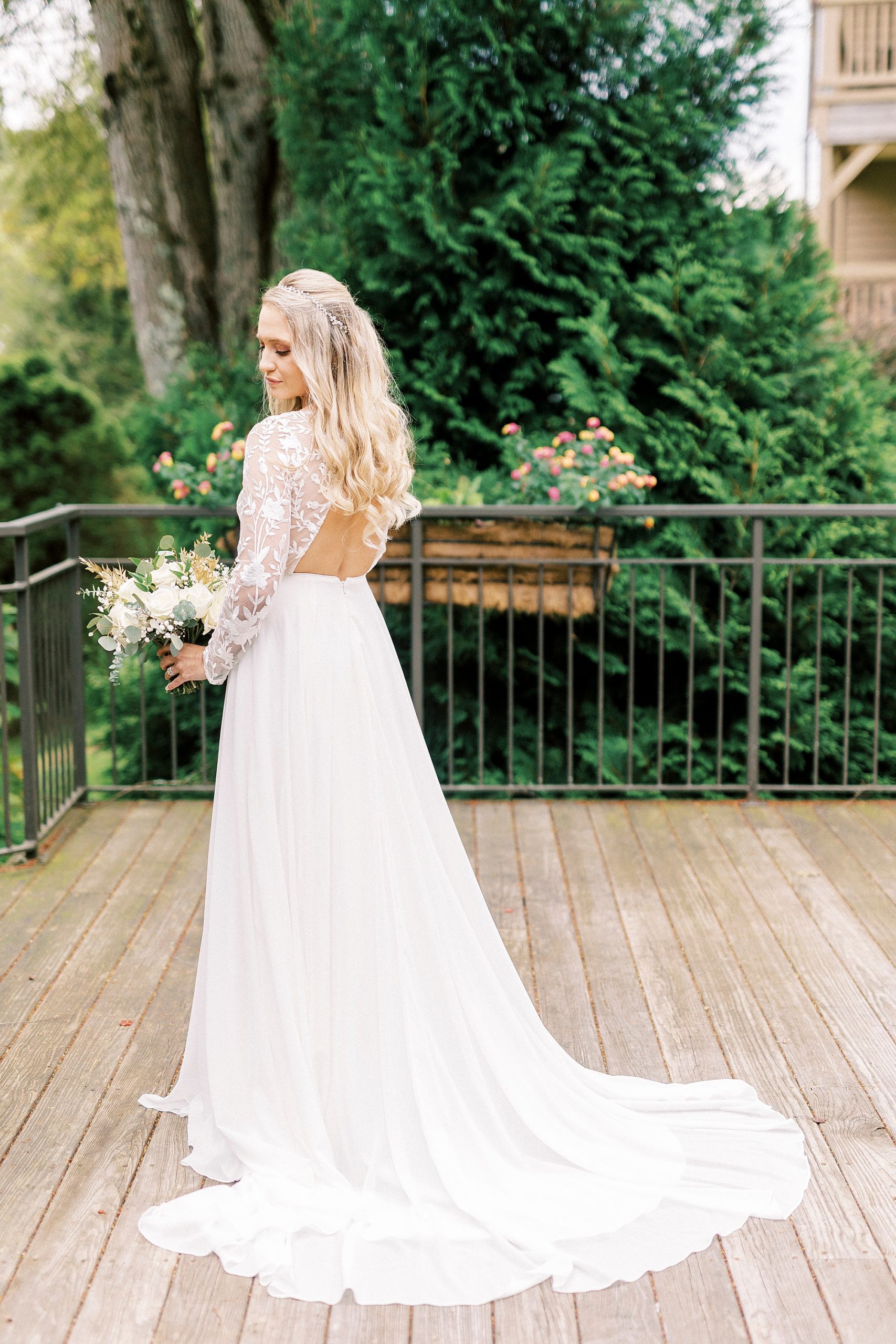 bride poses on wooden balcony yin wedding gown with lace sleeves