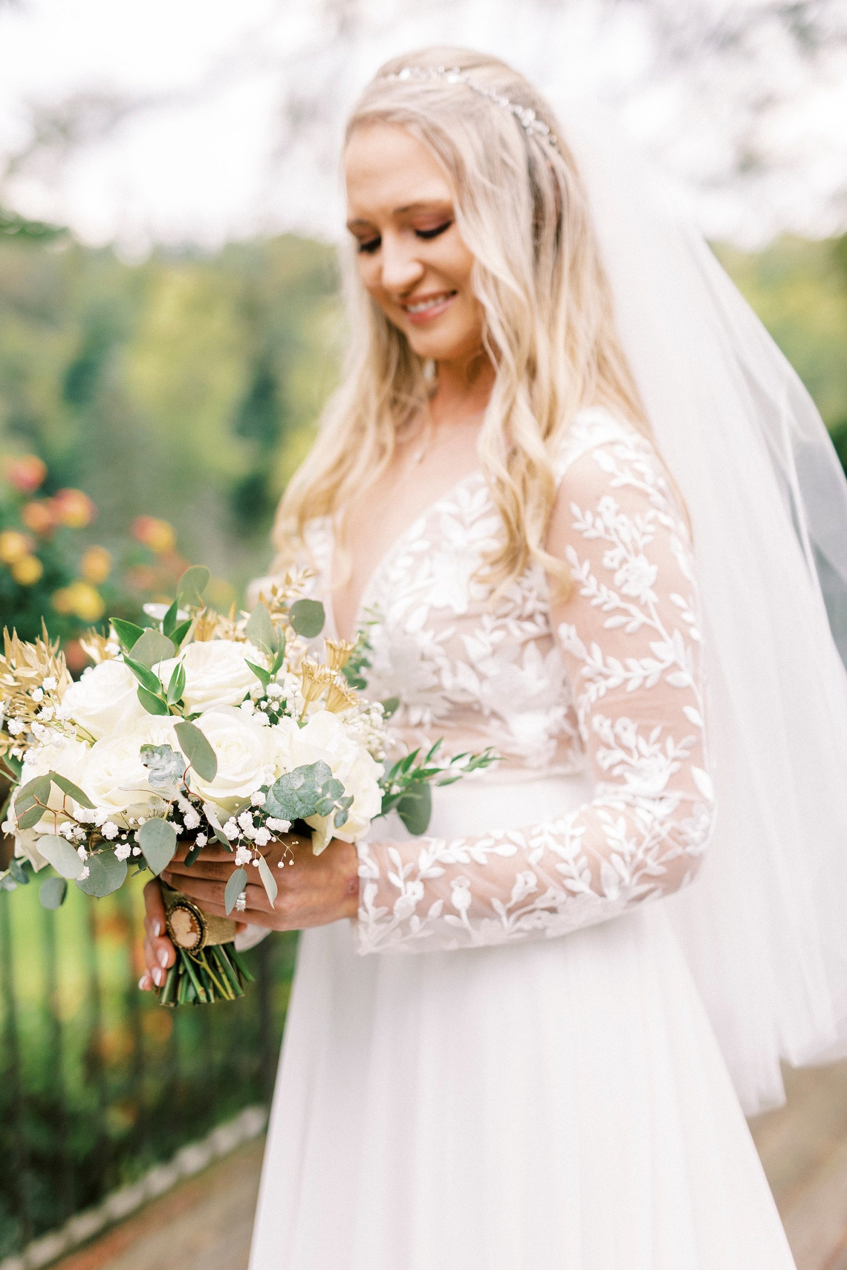 bride stands holding bouquet with white flowers before fall wedding at Chetola Resort