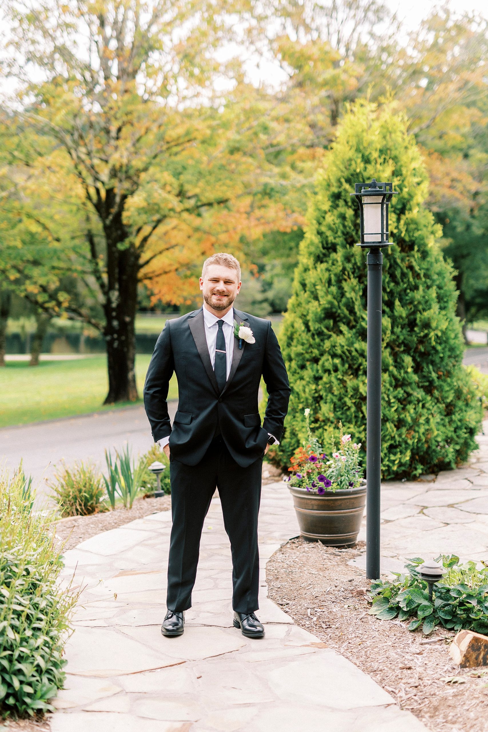 groom stands on pathway at Chetola Resort