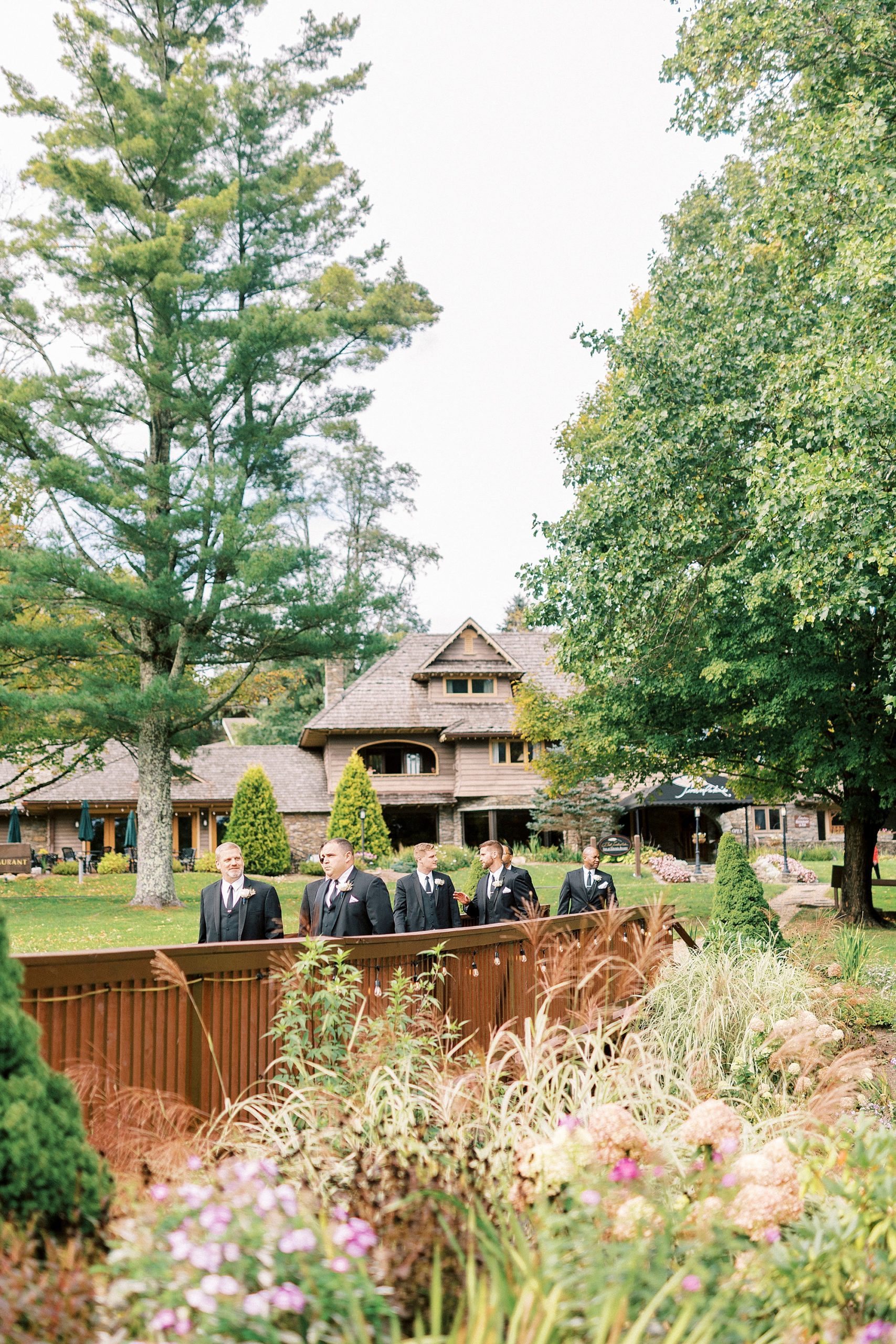 groomsmen walk across wooden bridge at Chetola Resort