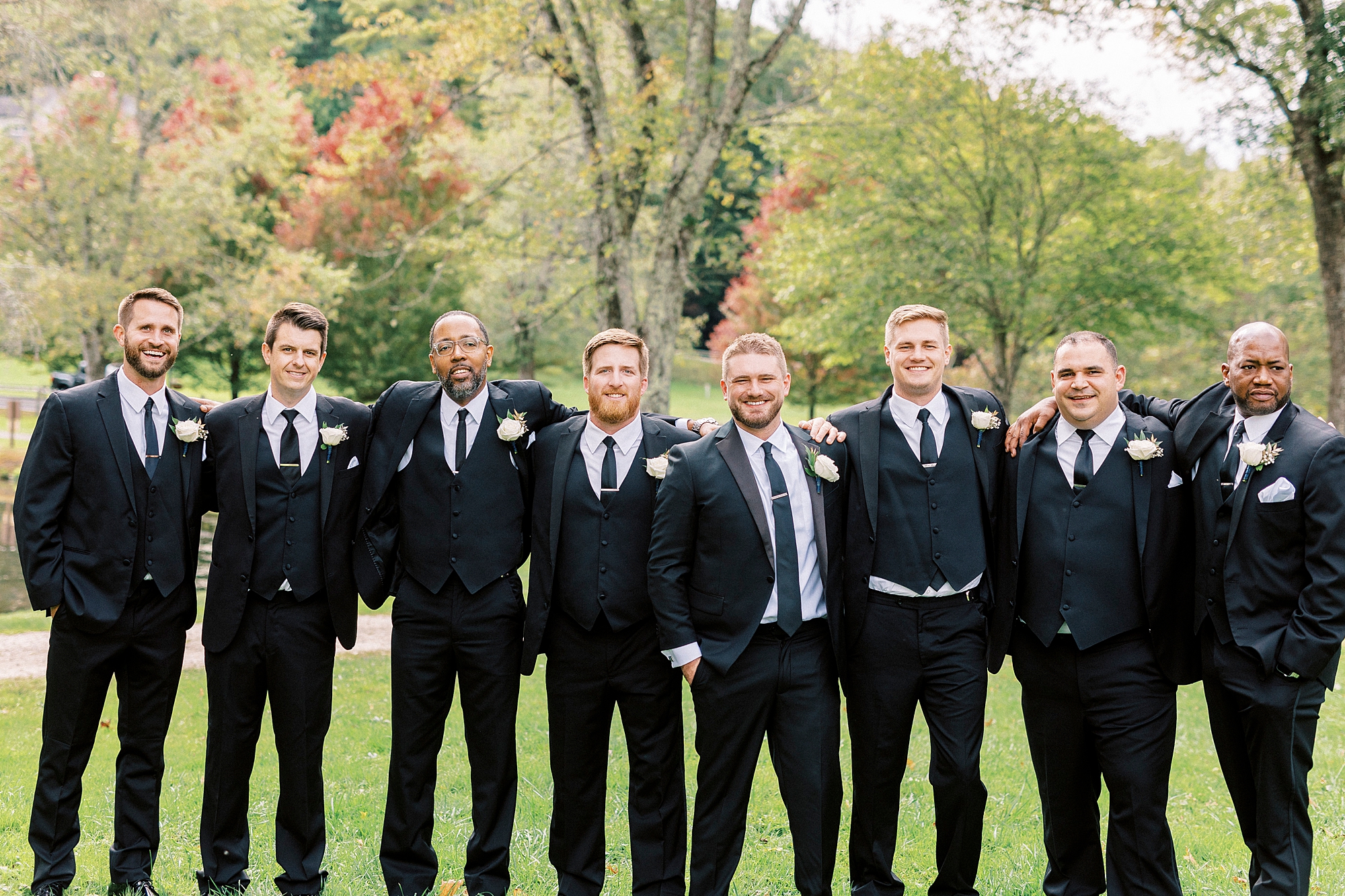 groom hugs groomsmen in black suits