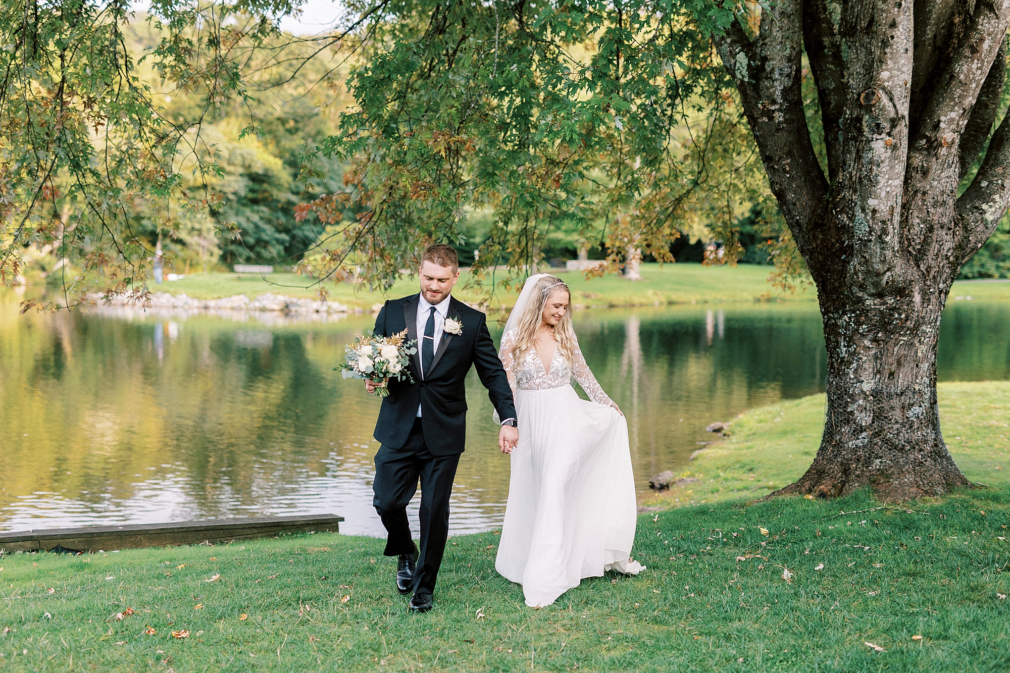 bride and groom walk together by waterfront at Chetola Resort