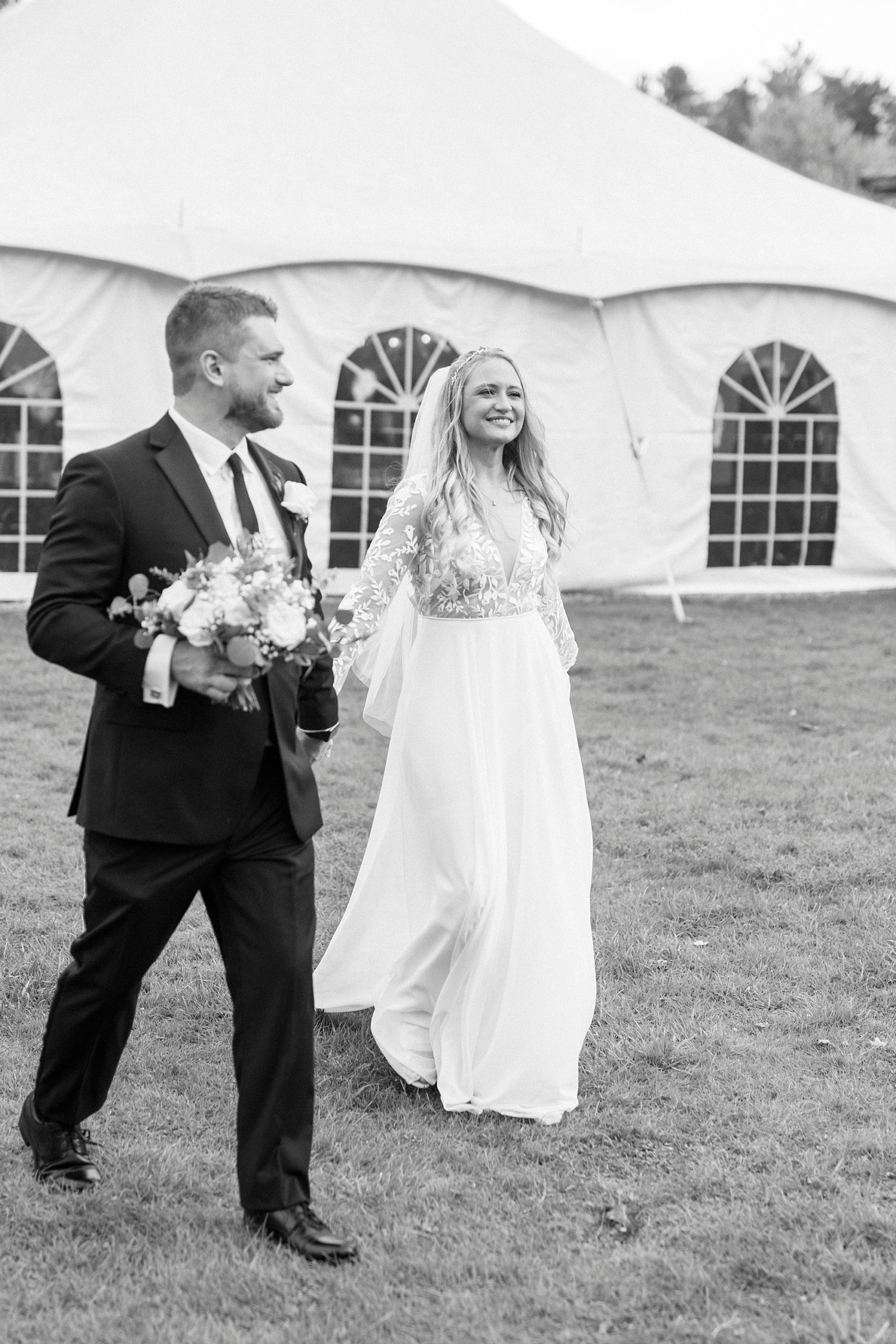 bride and groom hold hands walking by tent for reception at Chetola Resort