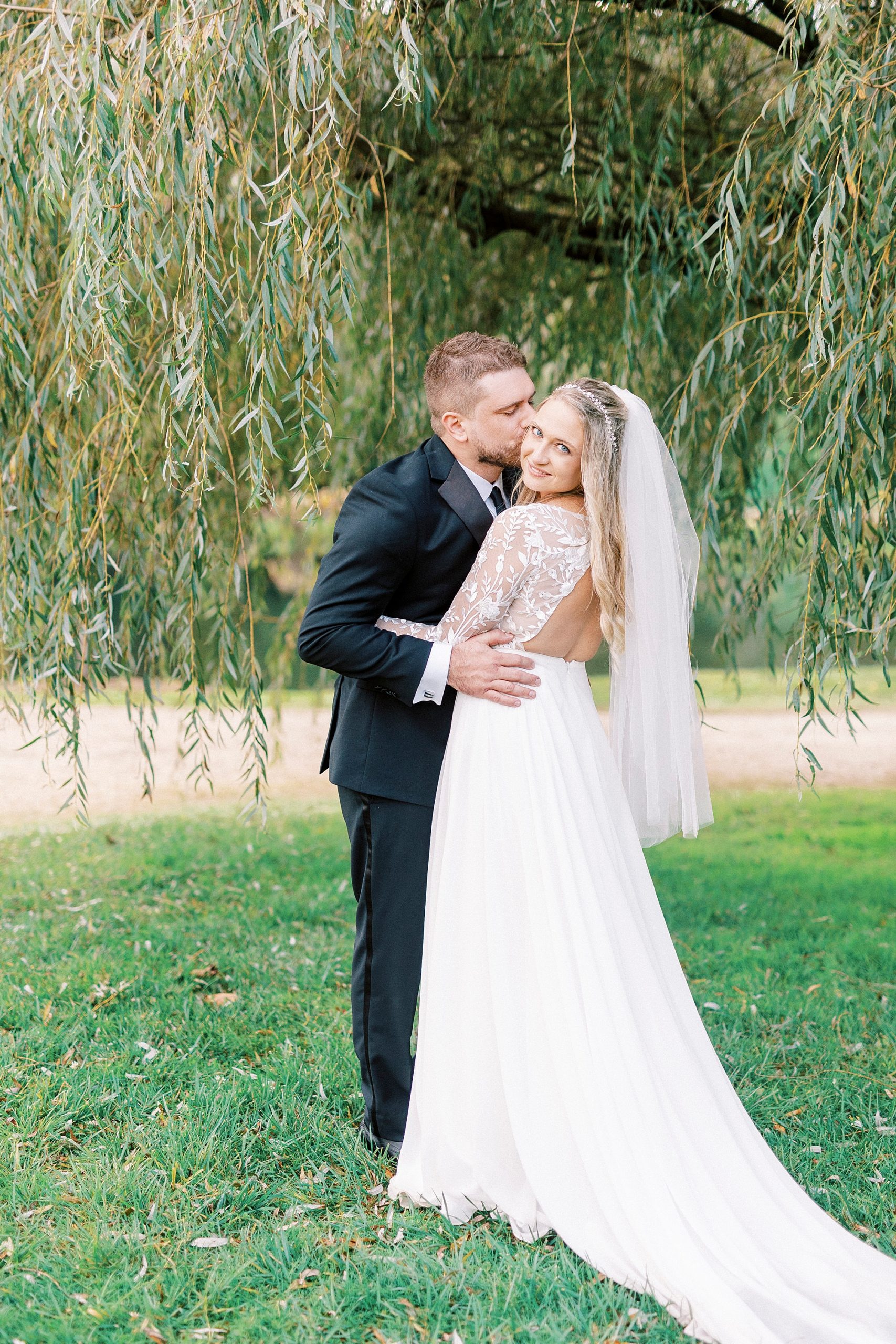 groom kisses bride's cheek during fall wedding photos