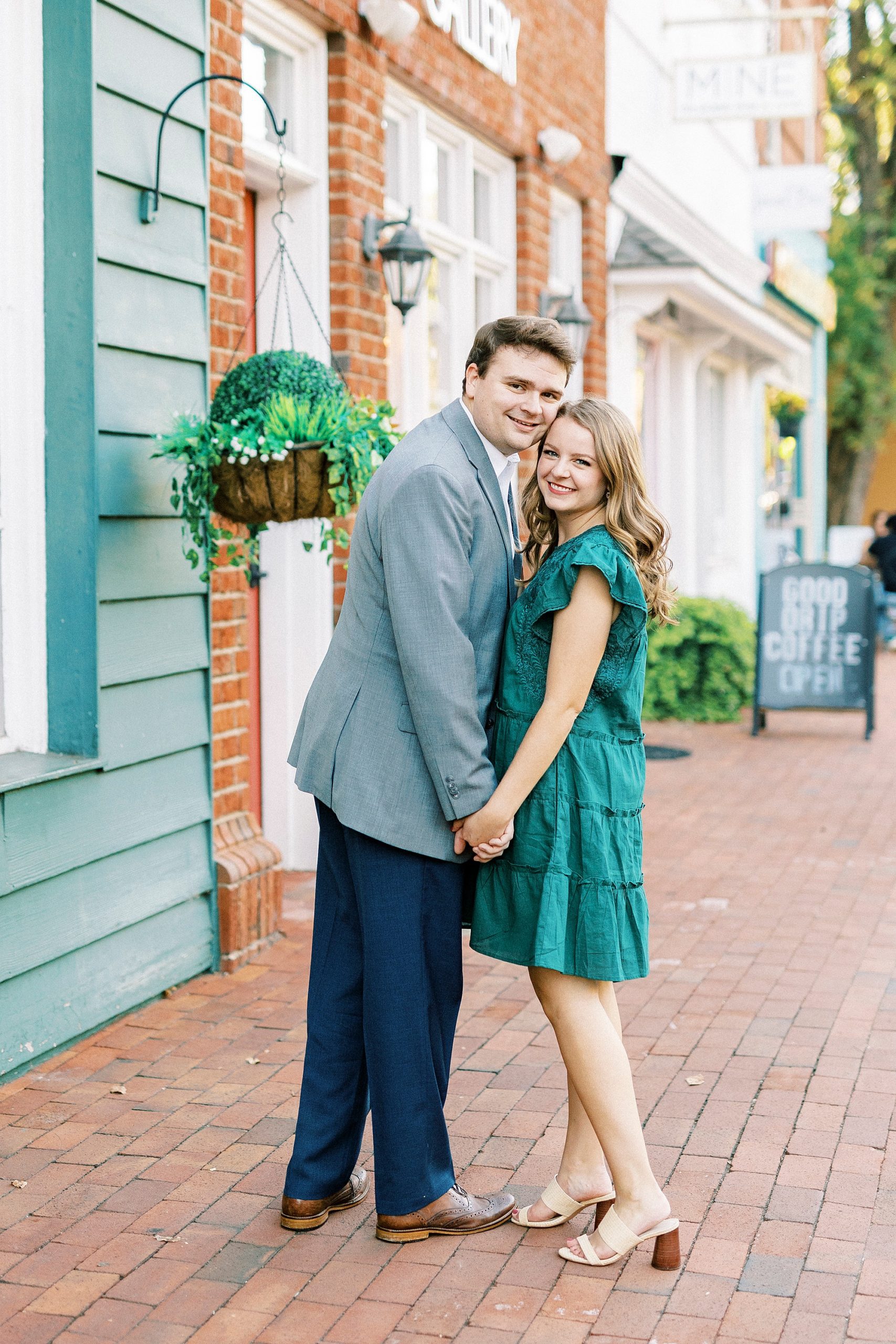 engaged couple hugs on sidewalk in Downtown Davidson