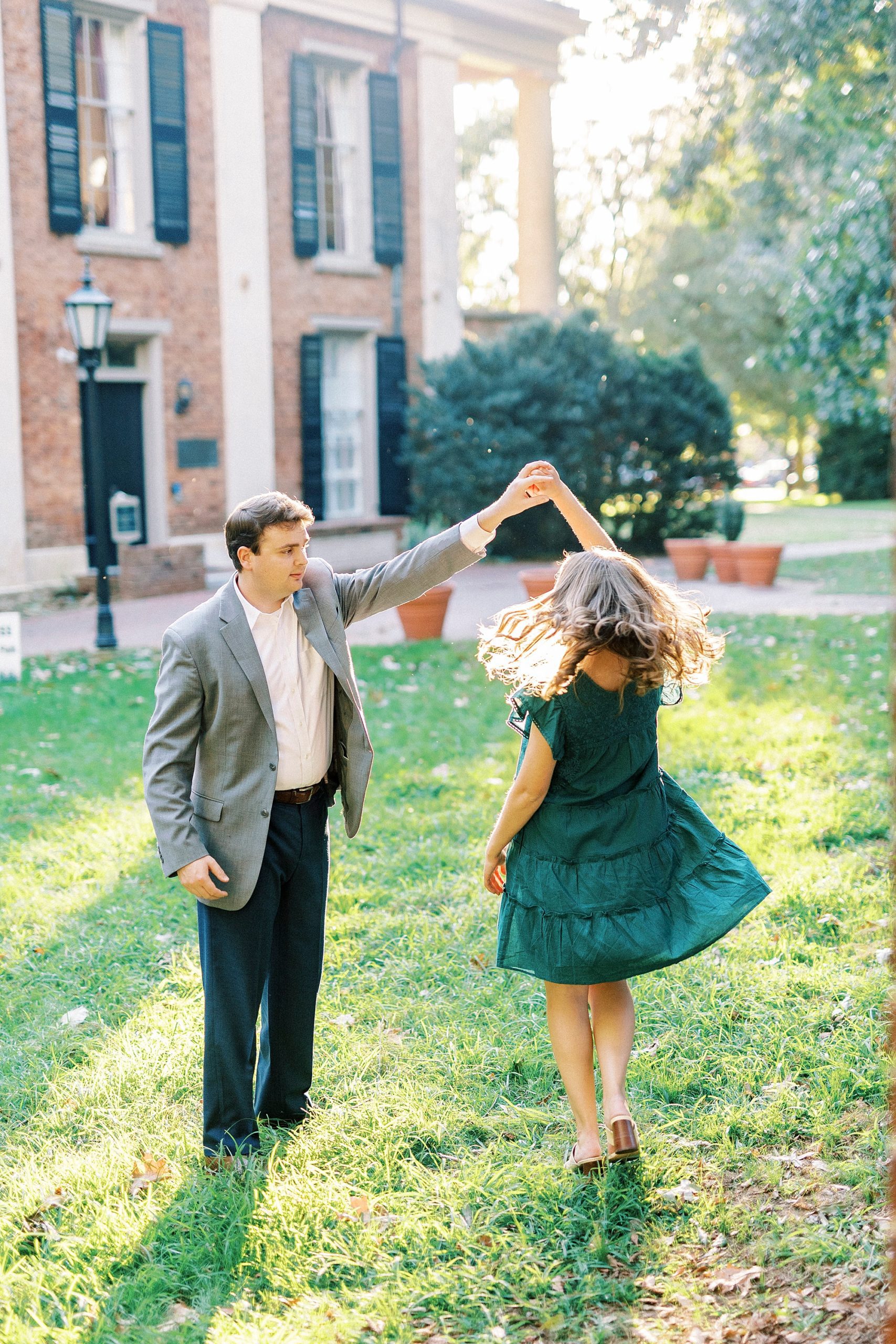 groom twirls bride during portraits on lawn in Downtown Davidson