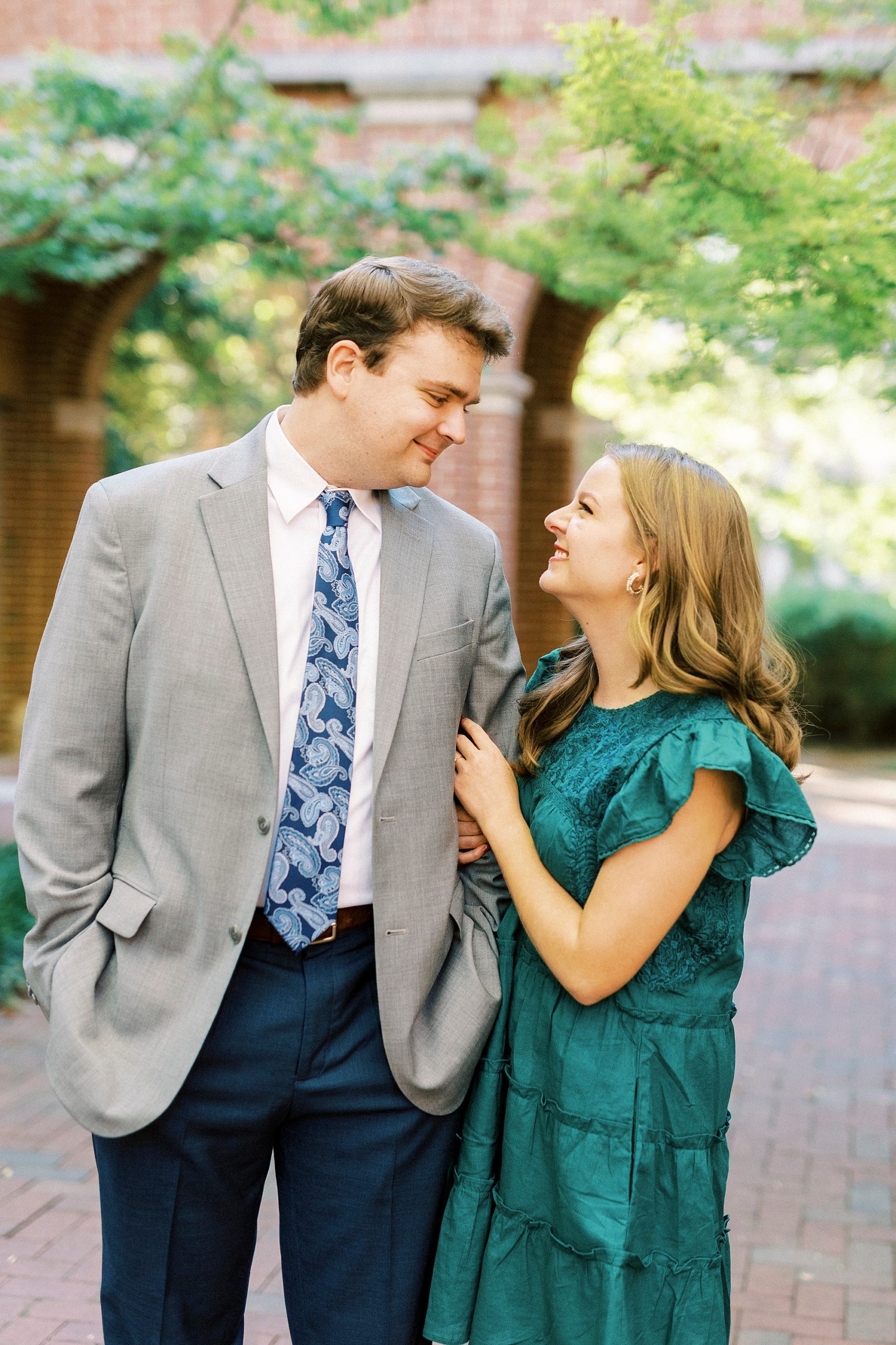 bride in teal dress smiles up at groom during NC engagement photos