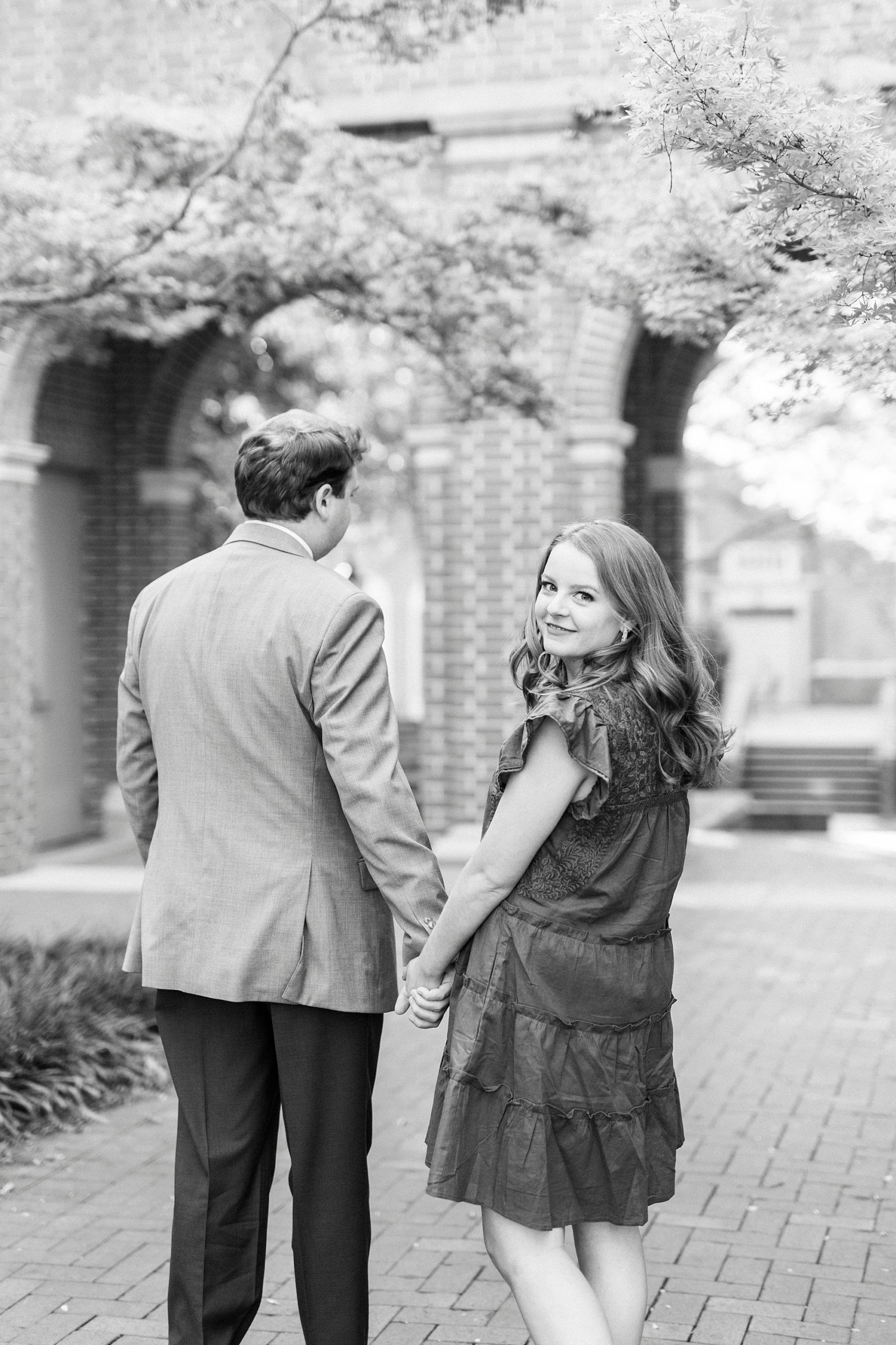 engaged couple holds hands walking through Downtown Davidson