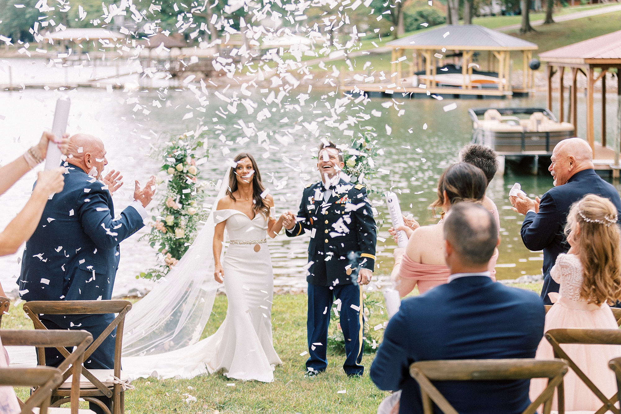 bride and groom laugh while guests toss flower petals after ceremony
