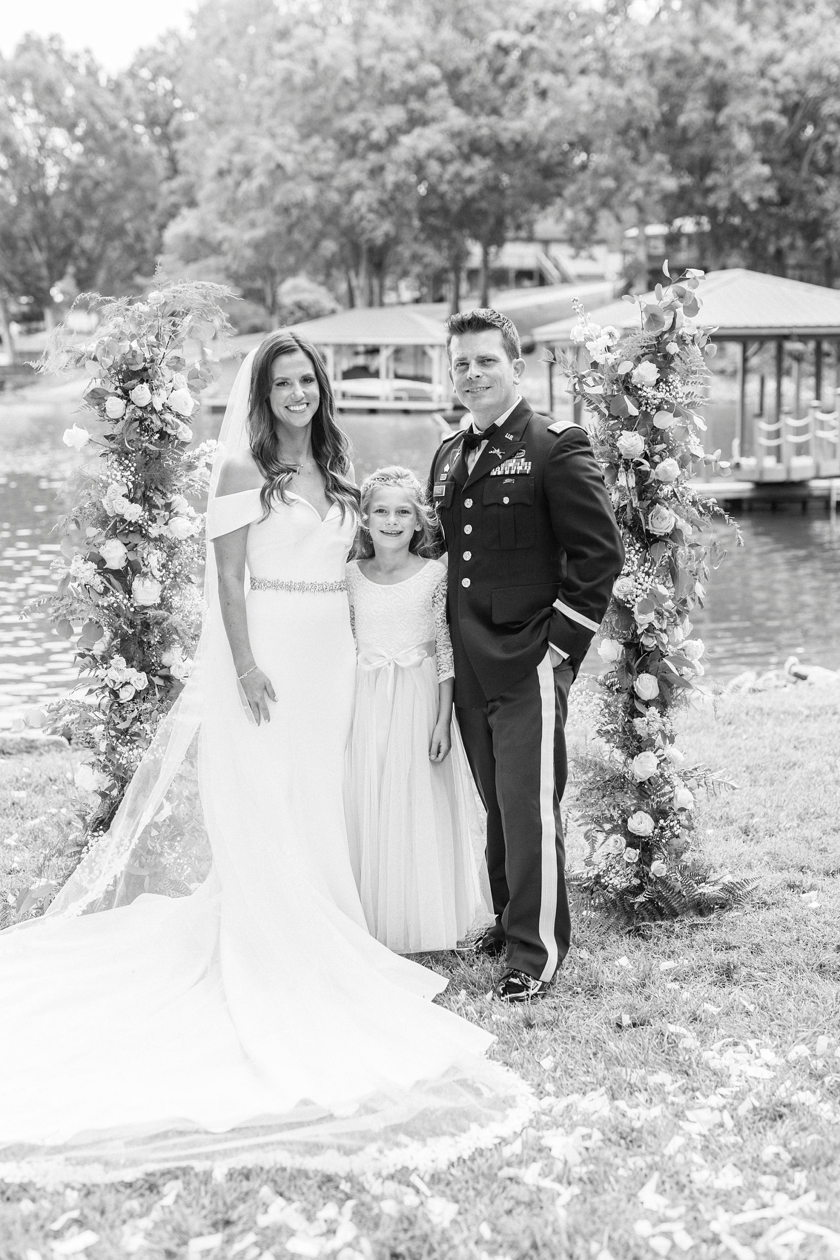 bride and groom pose with groom's daughter at alter