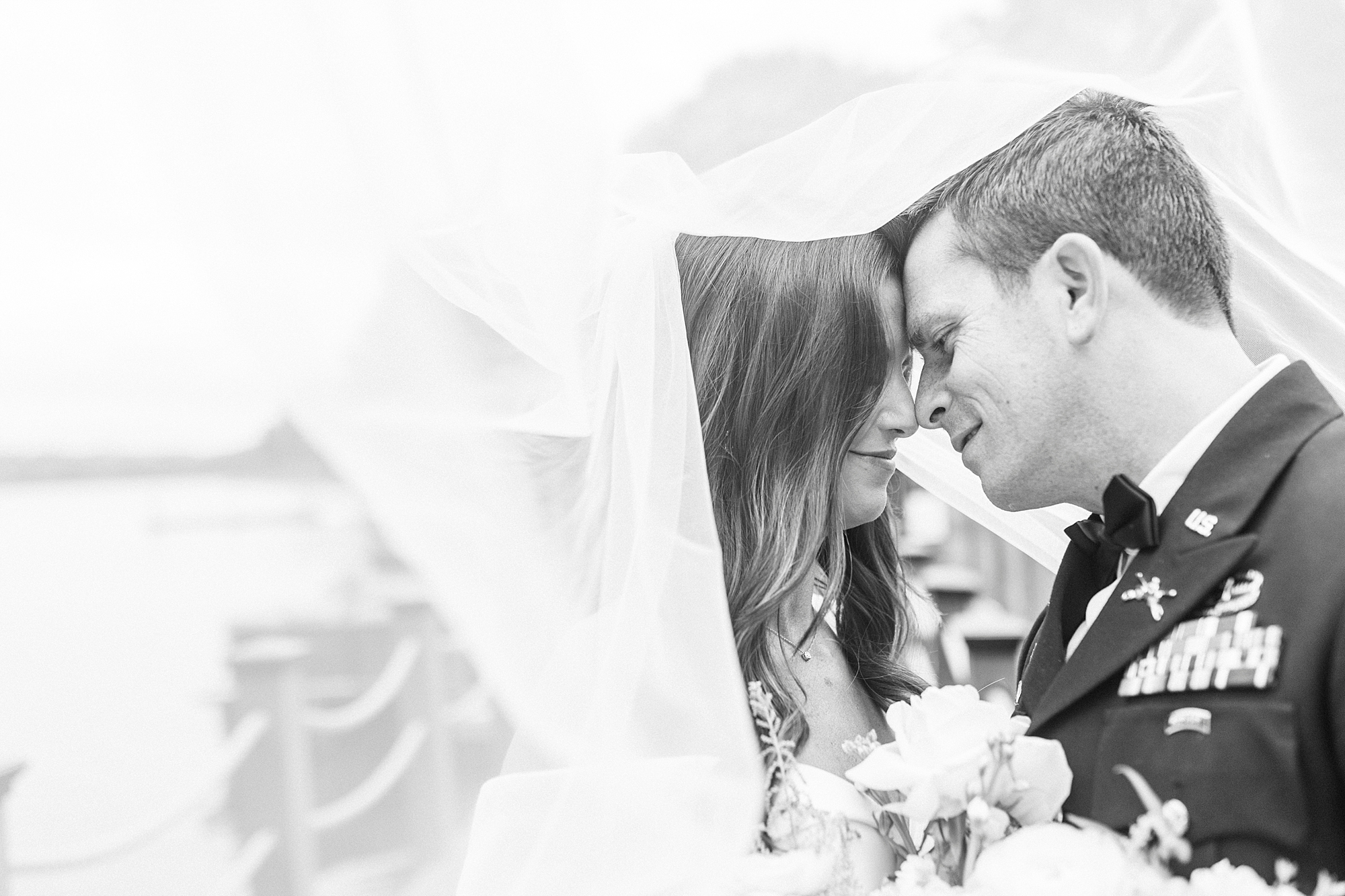 bride and groom hug under veil leaning for kiss