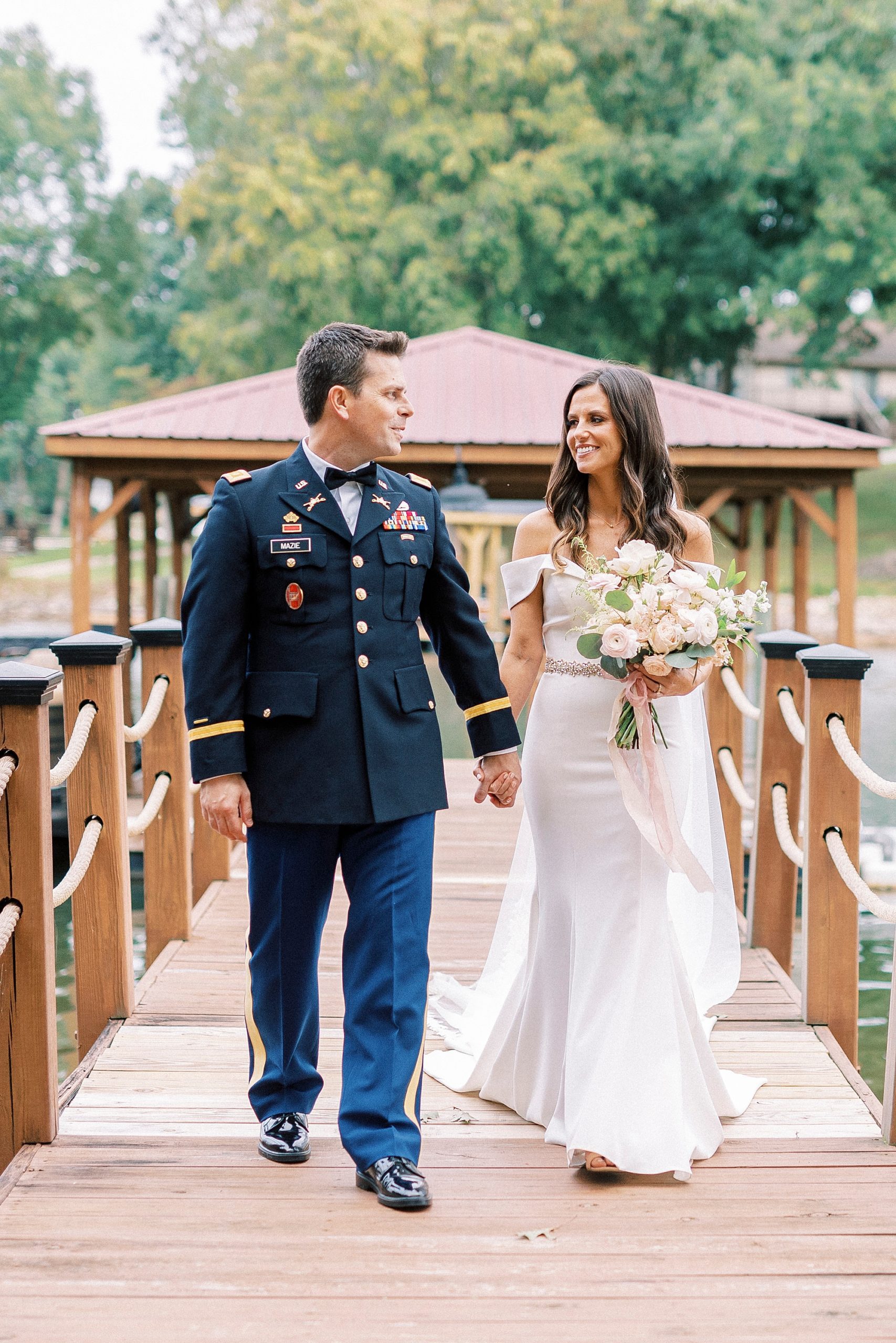 newlyweds hold hands walking over wooden dock at Lake Norman
