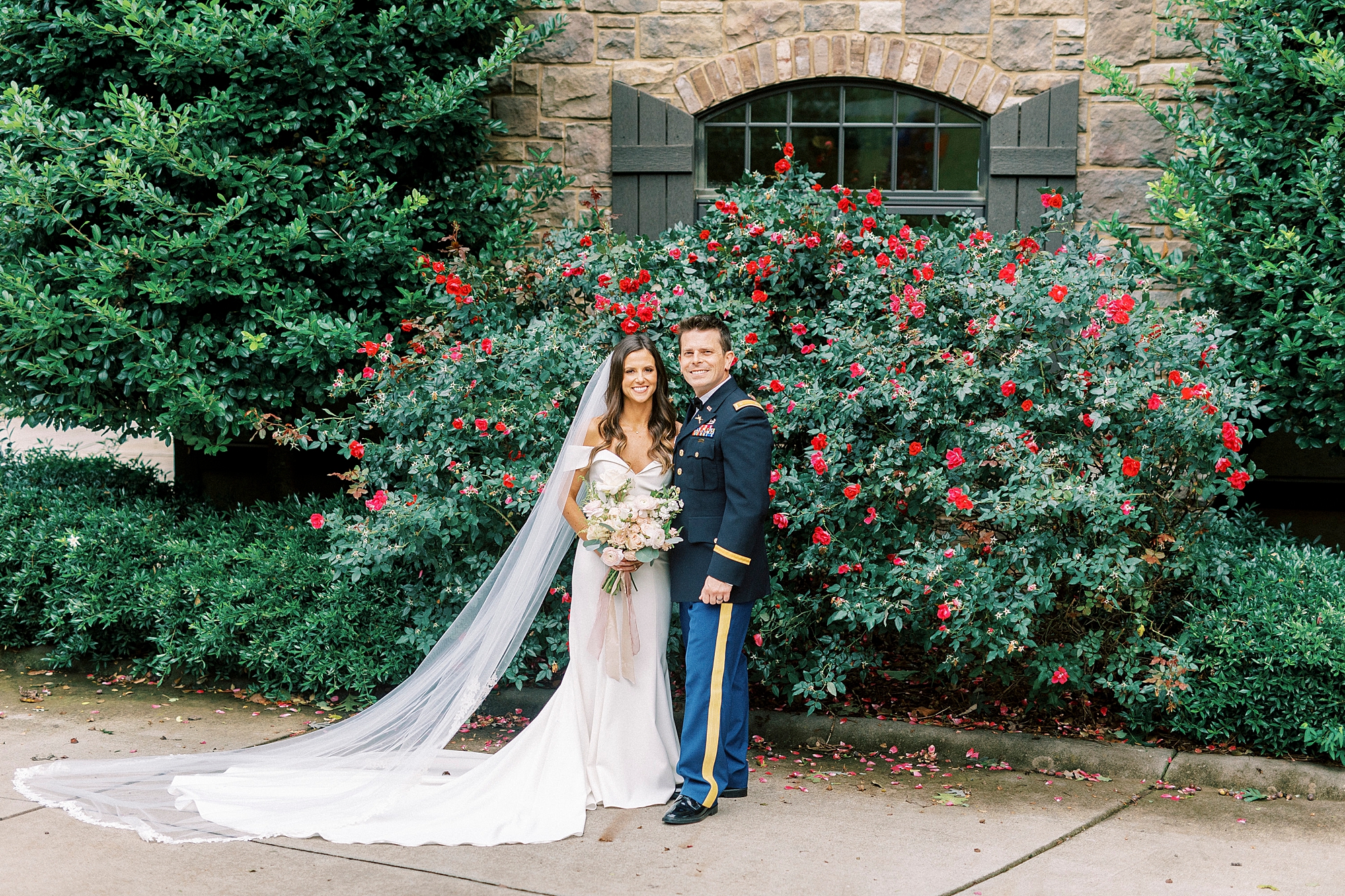 bride and groom pose by rose bush outside Lake Norman home