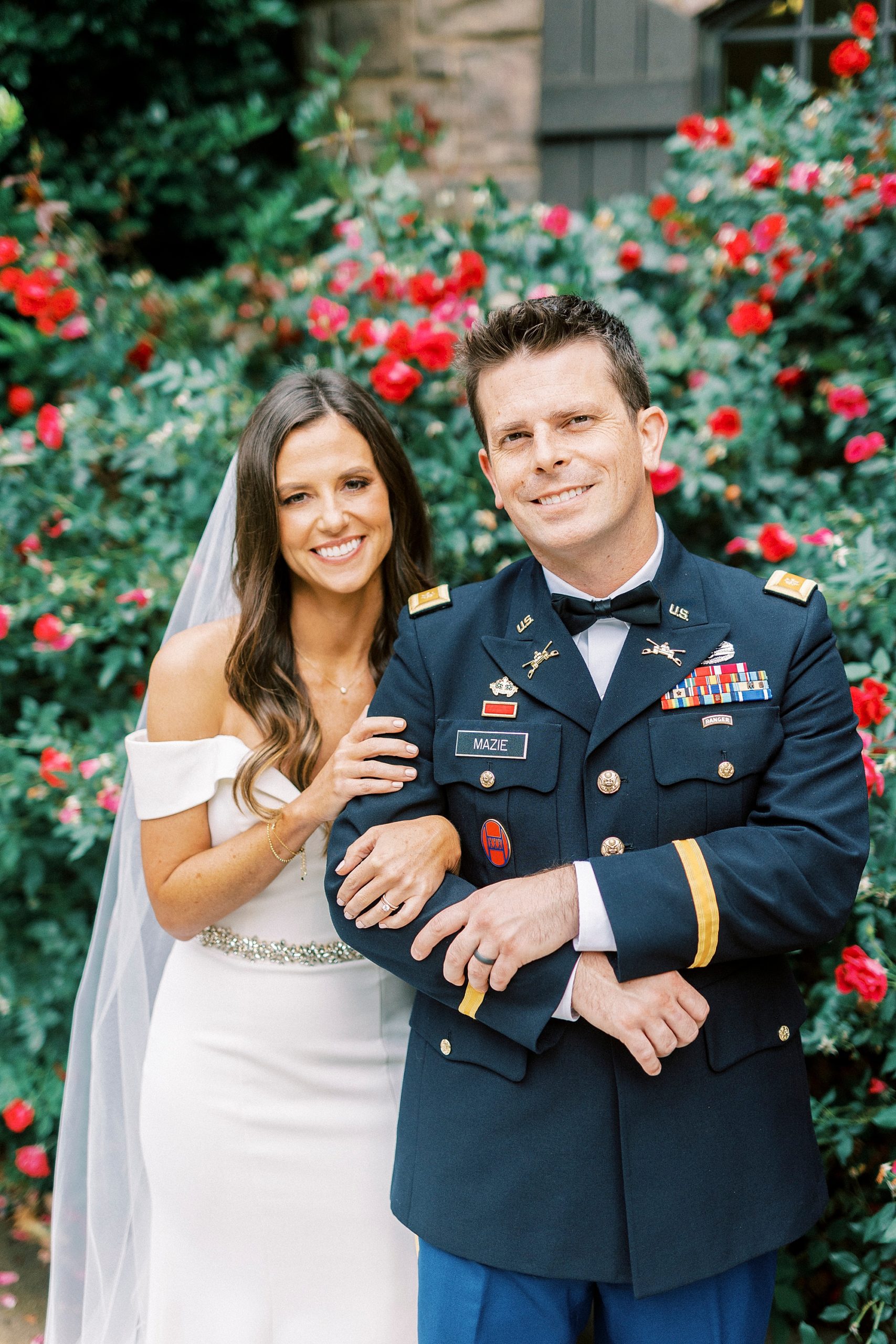 bride and groom hug by rose bush outside home in Lake Norman
