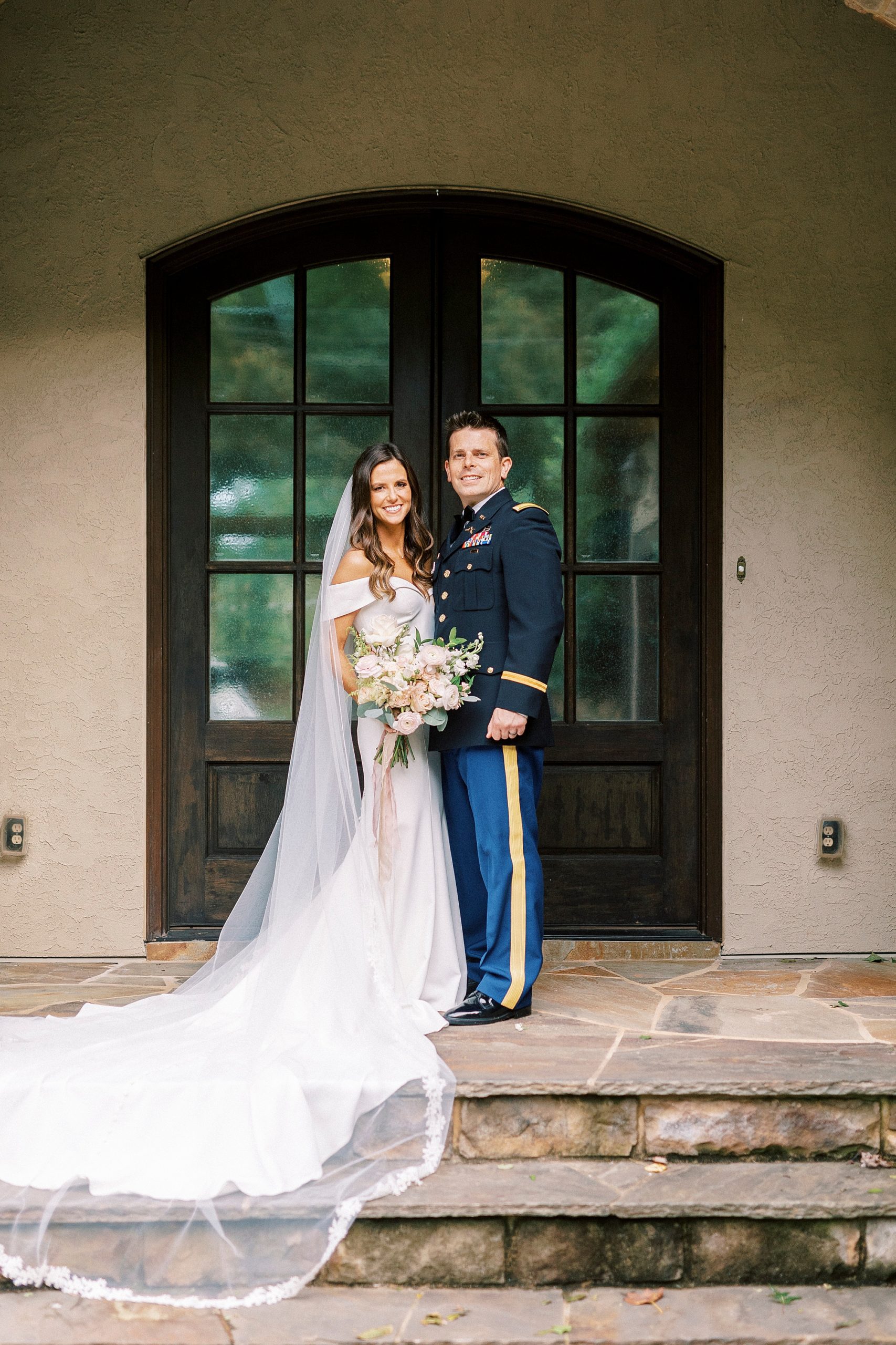 bride and groom stand on stone steps of home in Lake Norman