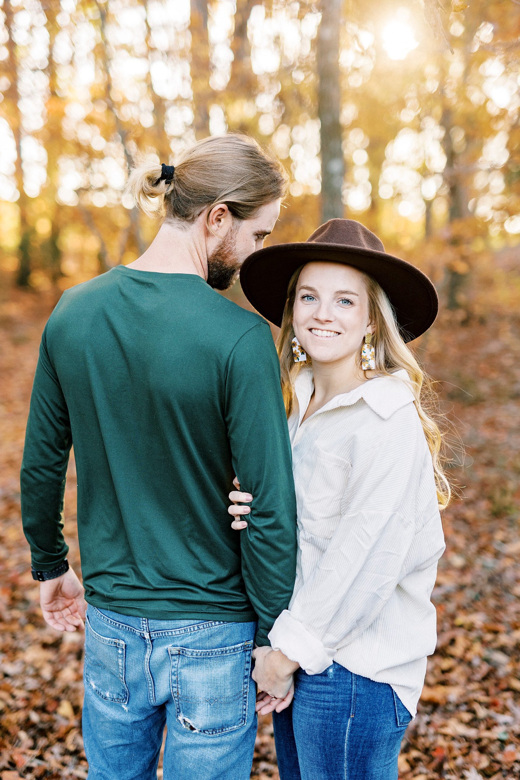 groom leans into bride while she holds his arm during chic fall engagement session