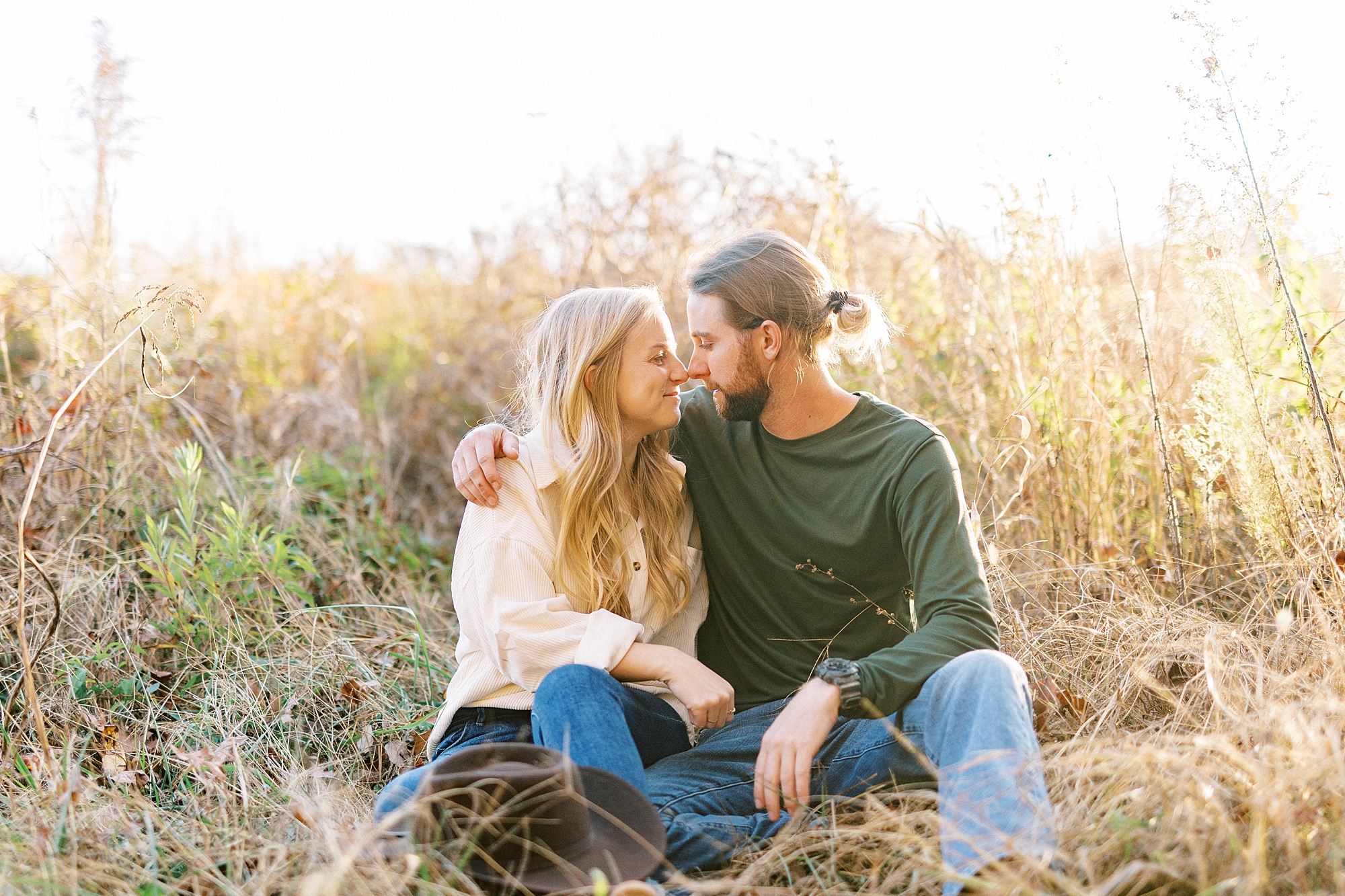 bride and groom lean heads together to kiss in field