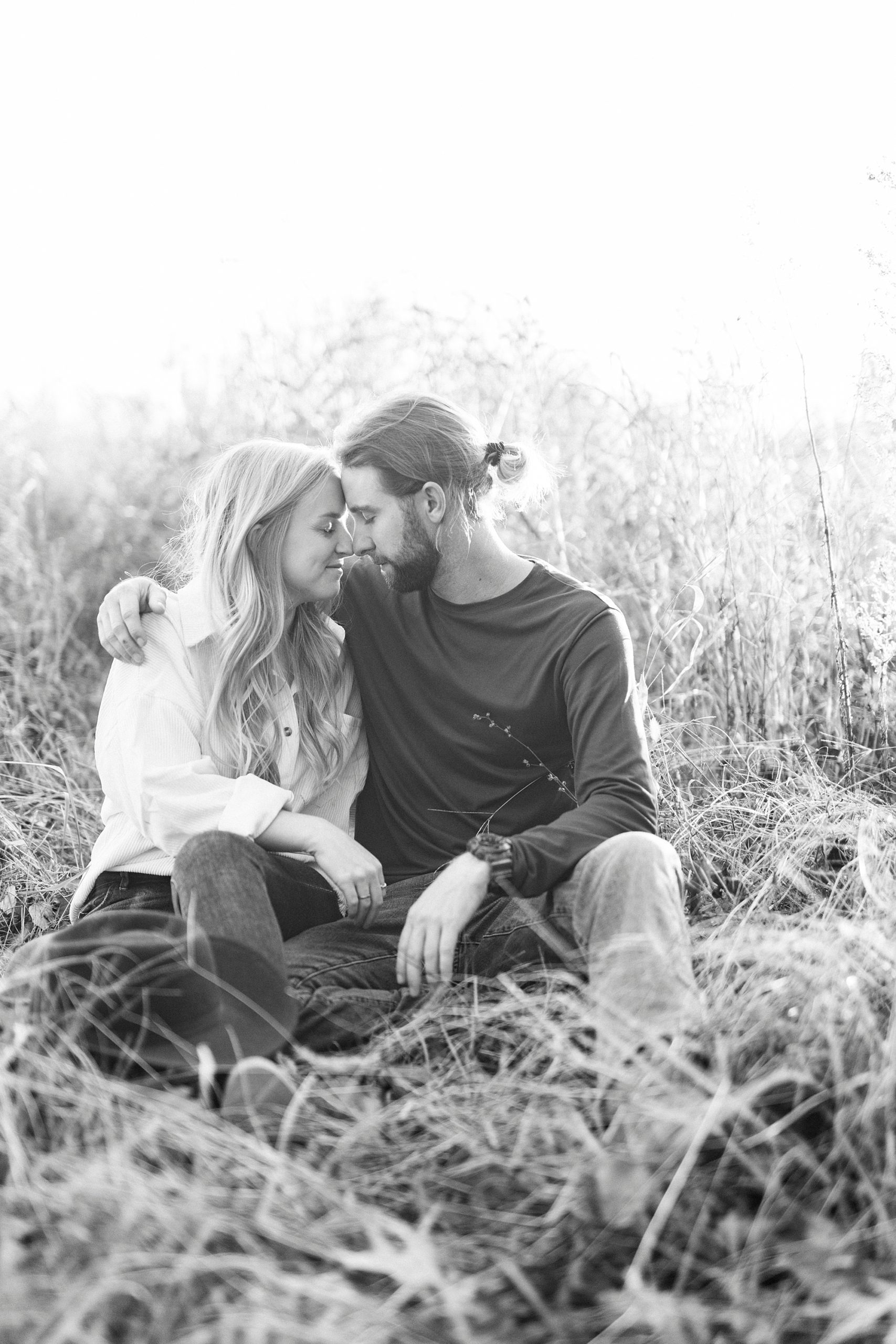 bride and groom lean heads together kissing in field