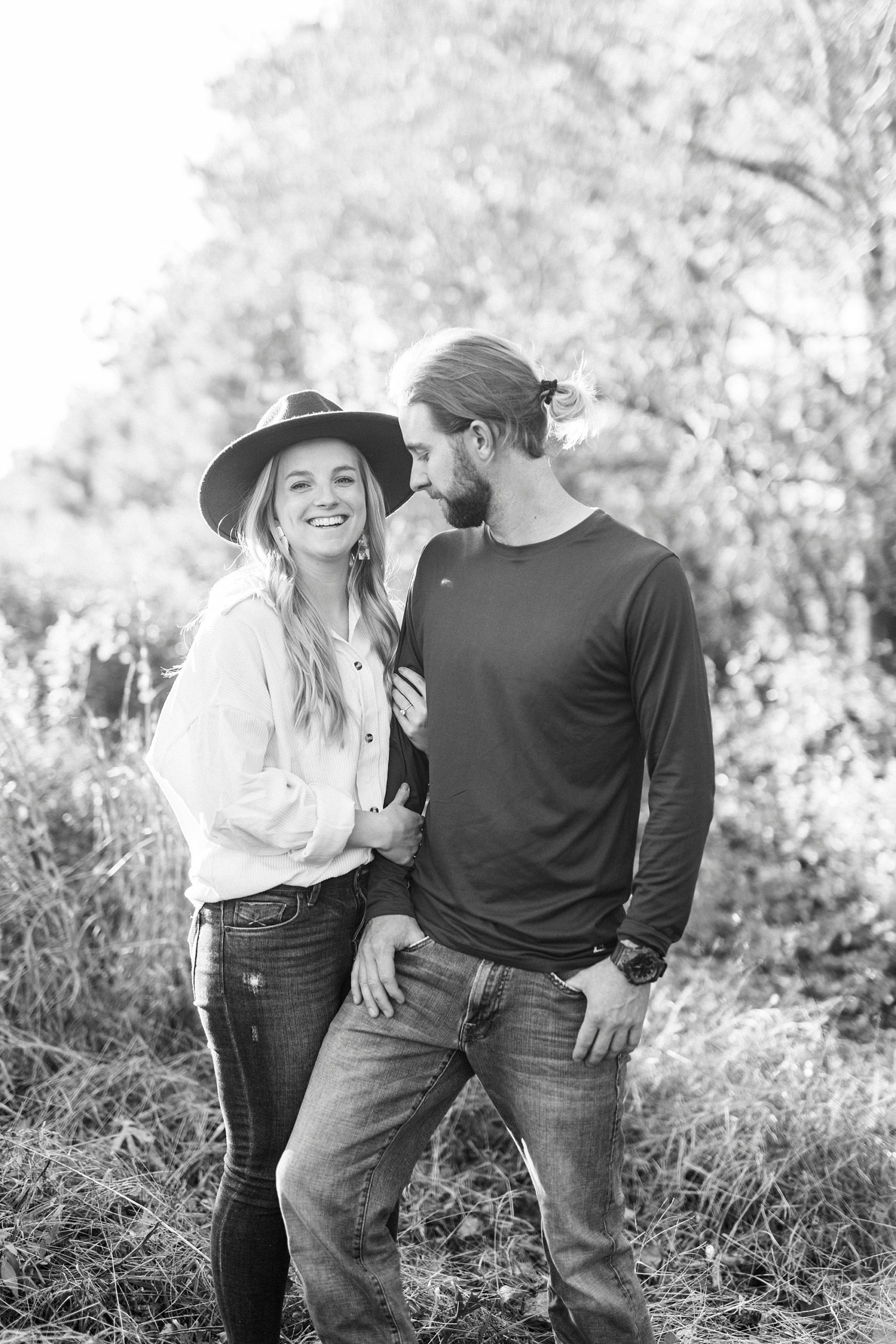 groom looks at bride smiling in field during chic fall engagement session