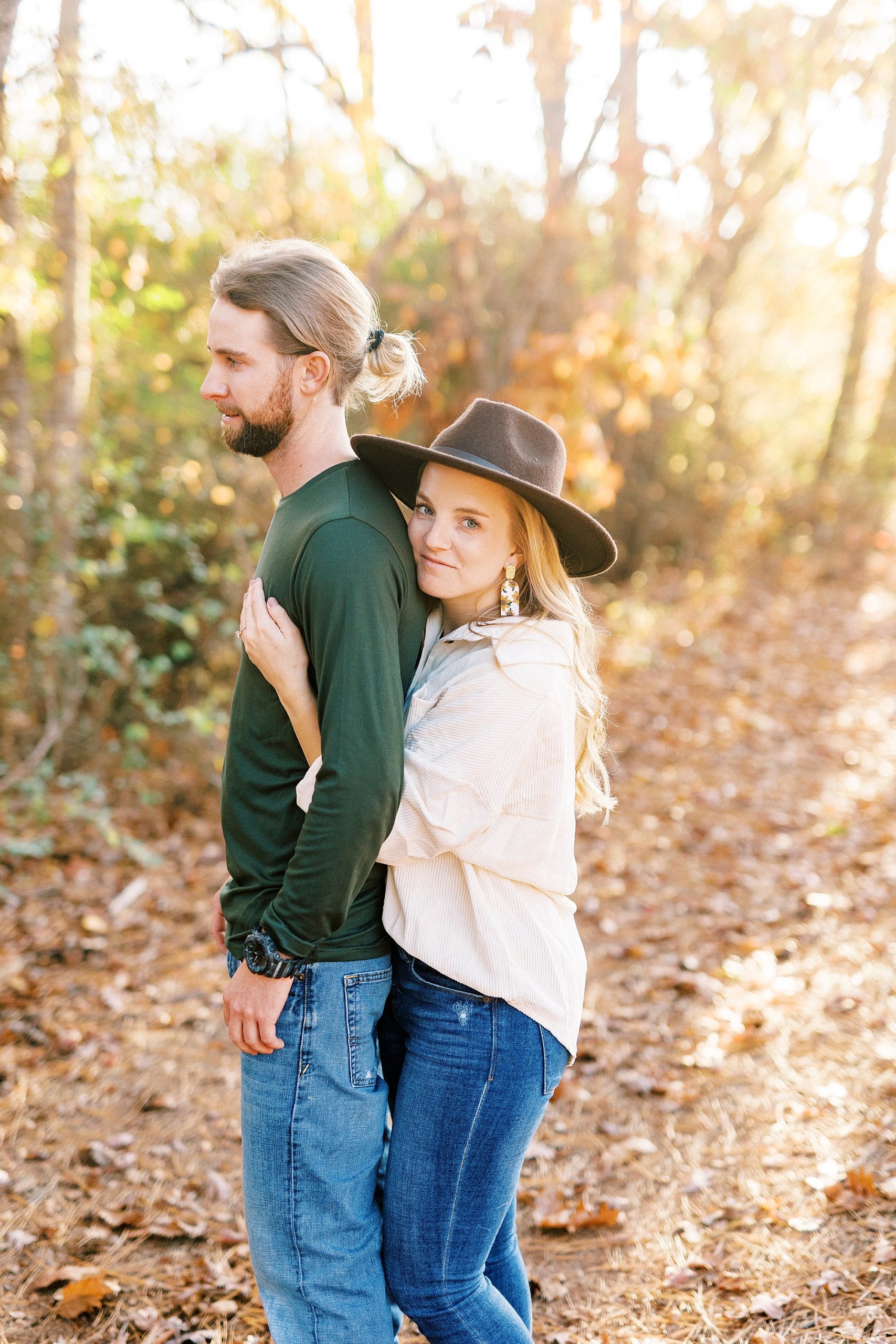 bride hugs groom from behind during chic fall engagement session