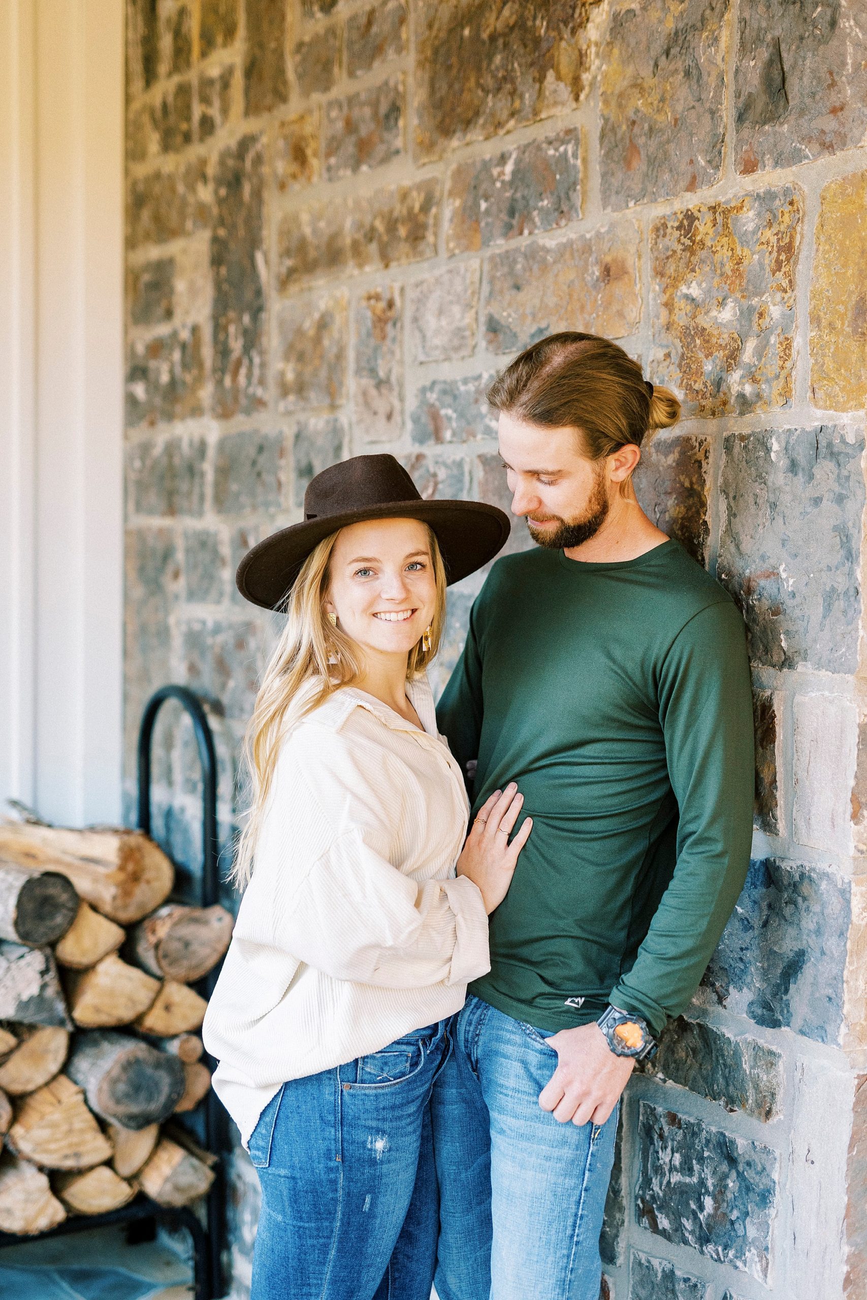 groom hugs bride against stone wall at home