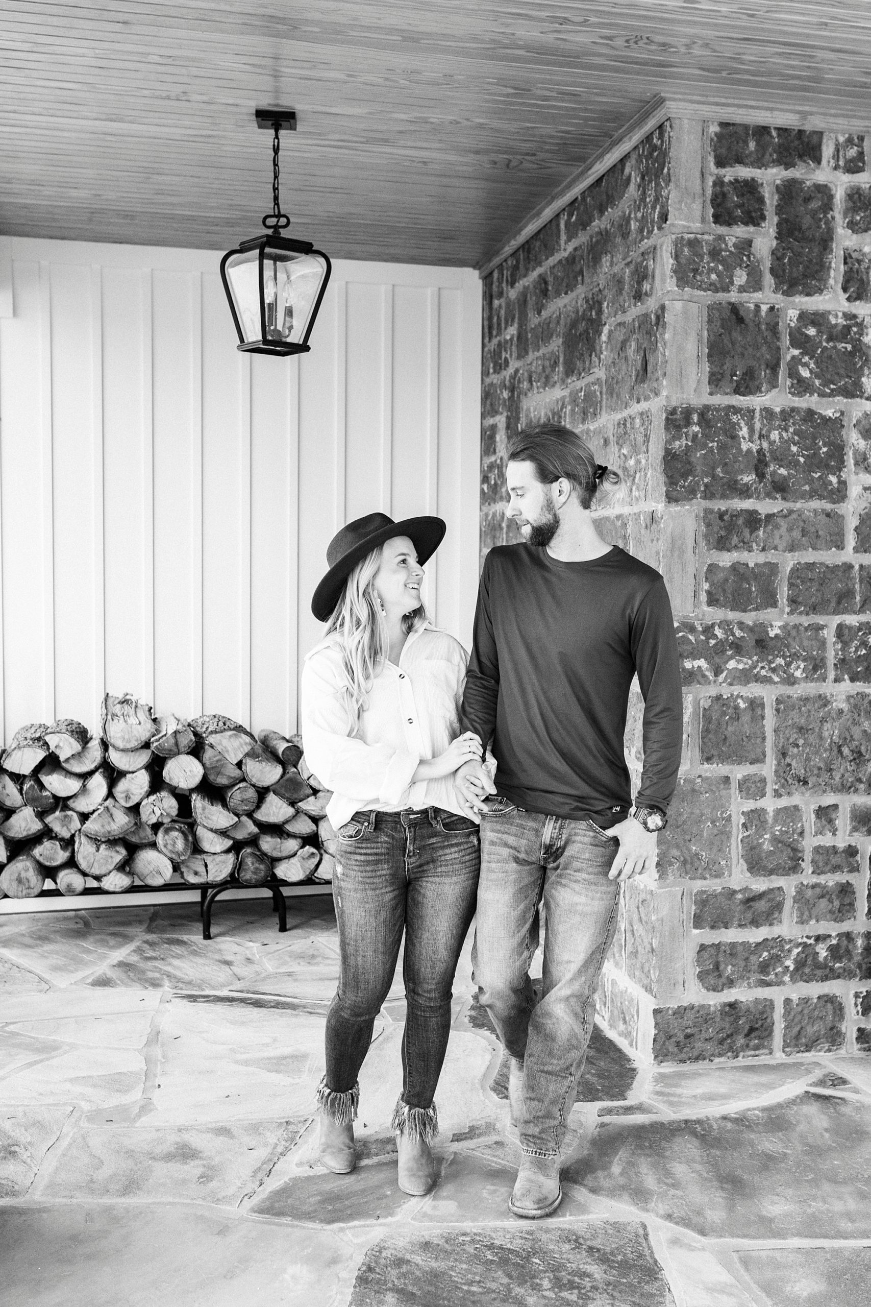 engaged couple leans against stone wall during chic fall engagement session