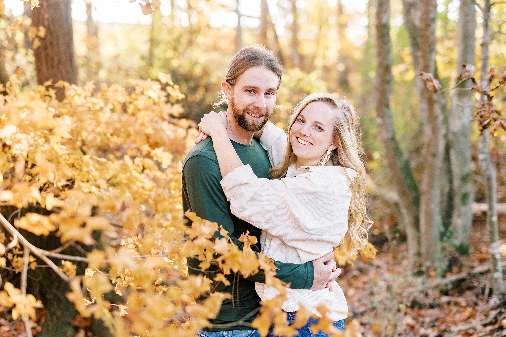 couple hugs looking at photographer in yellow tree