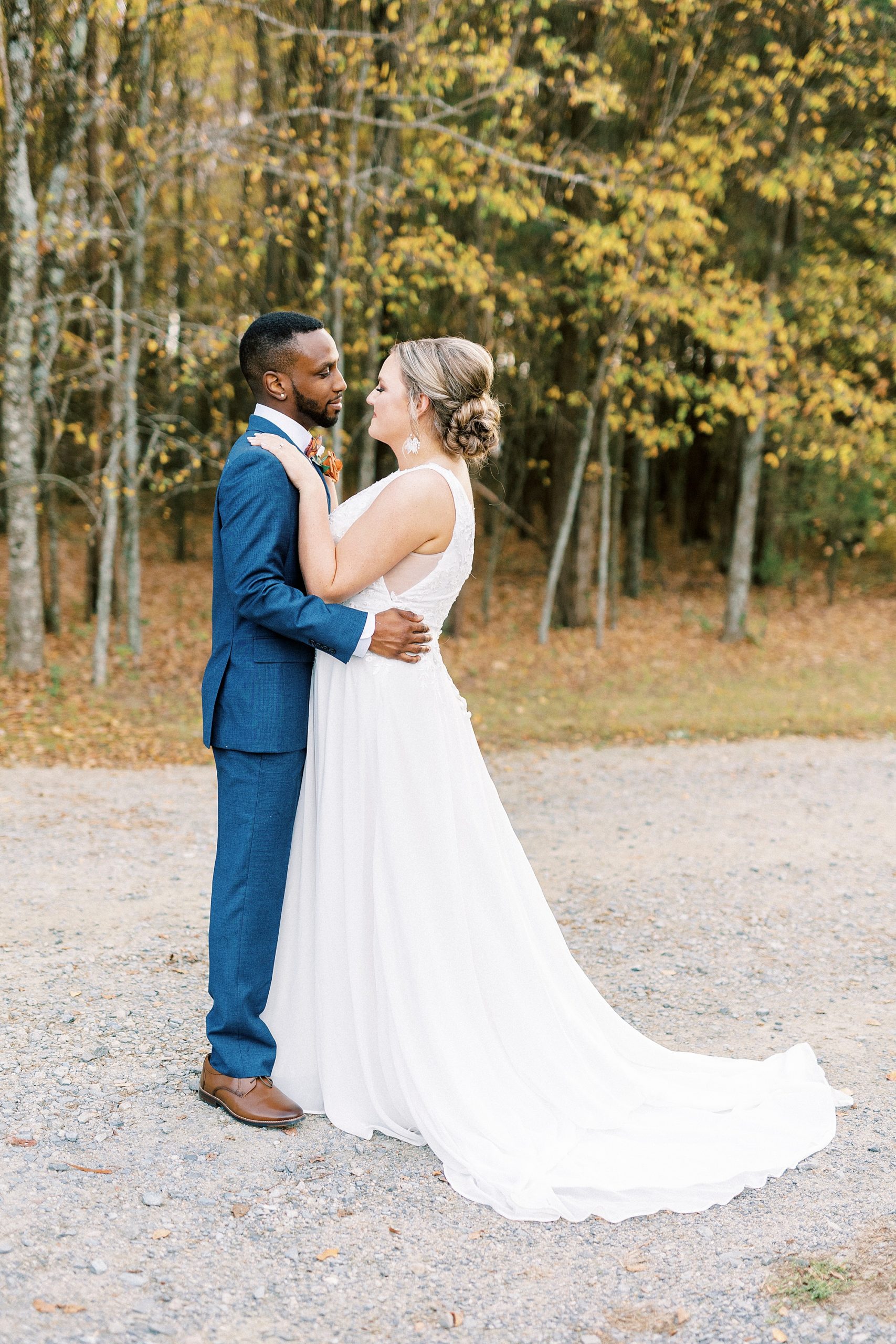 bride and groom hug on walkway during fall wedding portraits in Indian Trail Club NC