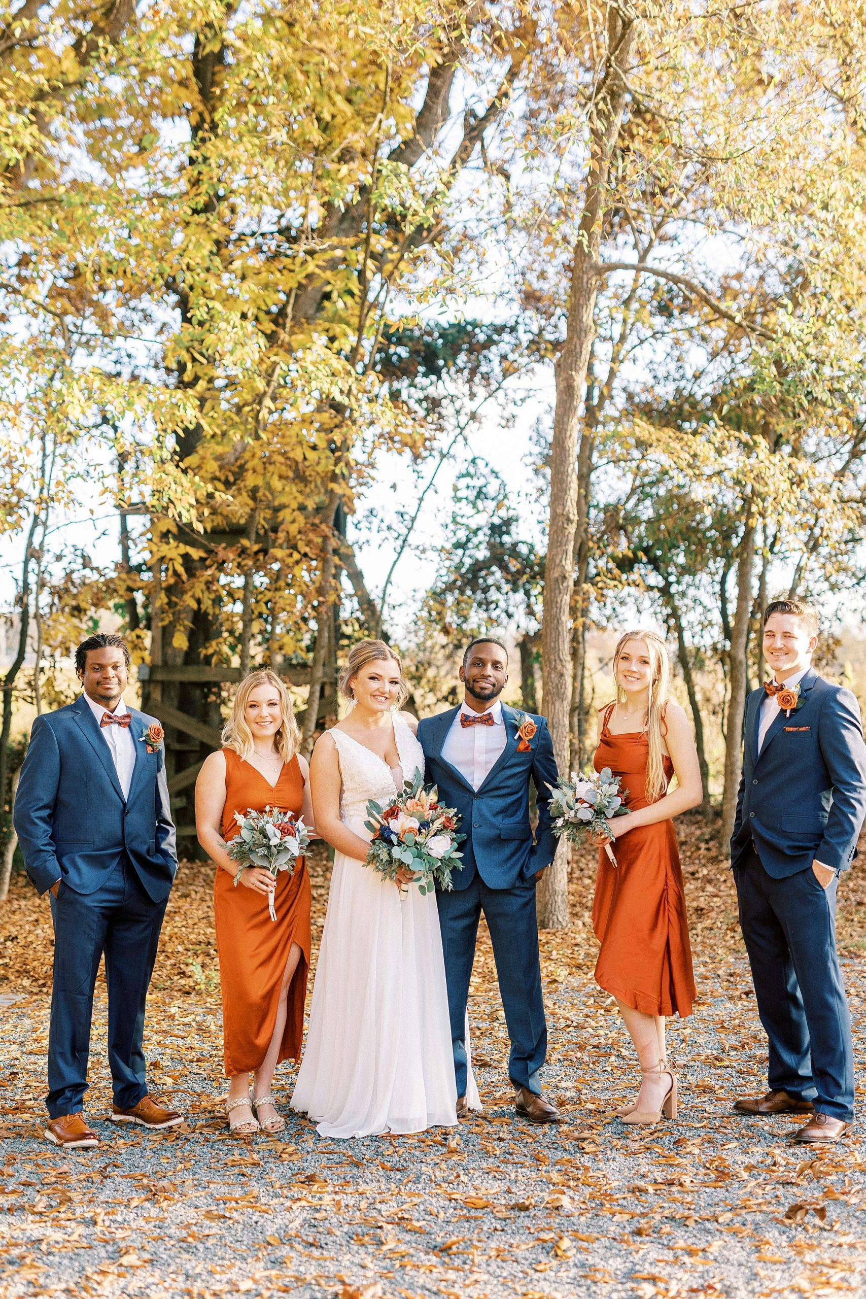 newlyweds stand with wedding party on hill at Bella Terra 