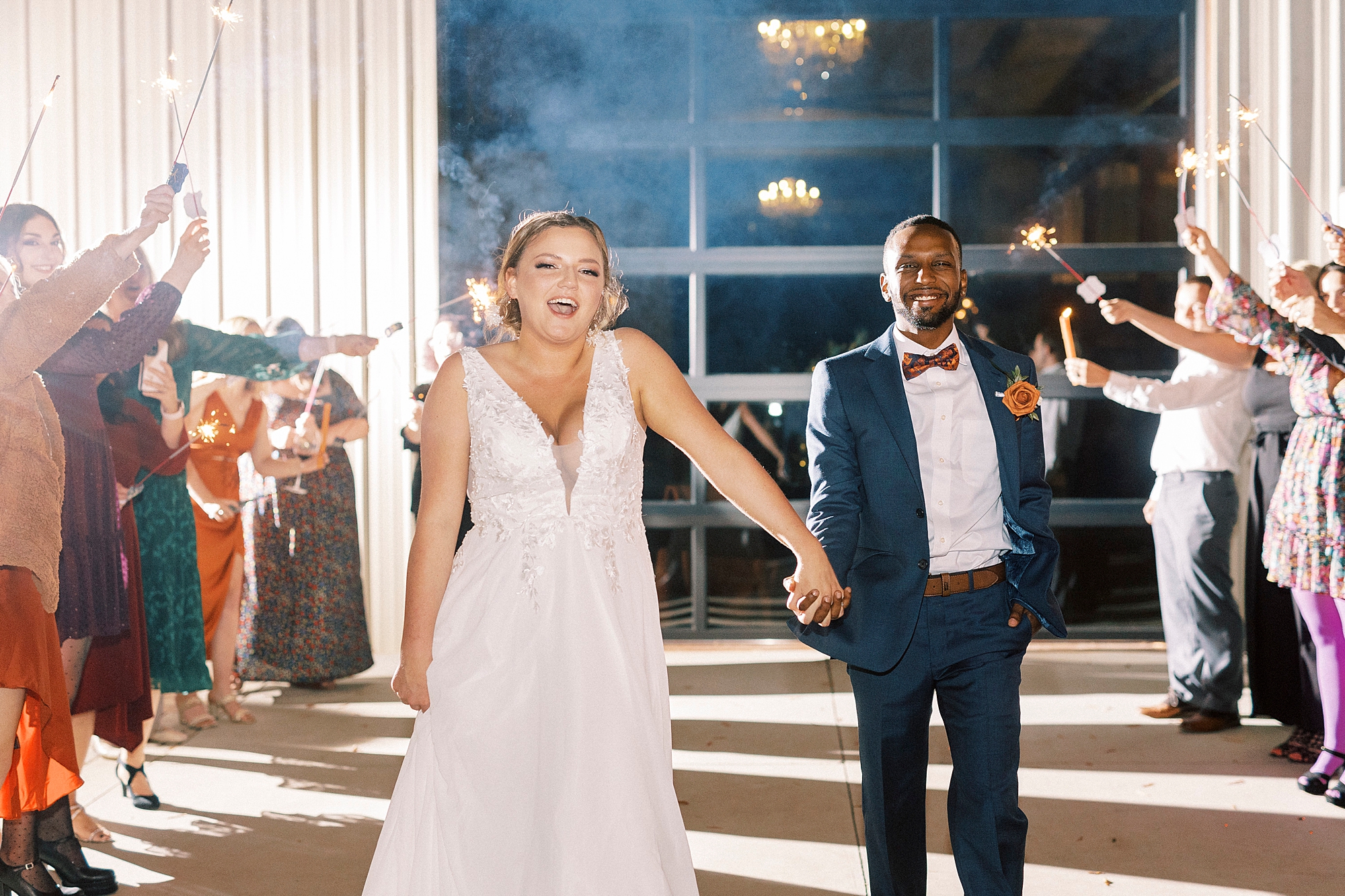 newlyweds smile and laugh during sparkler exit from Bella Terra Inc.