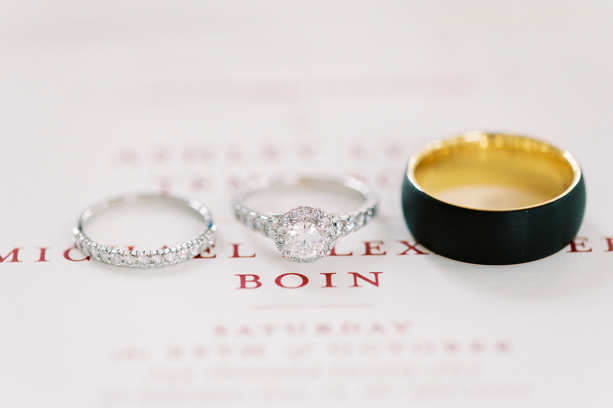 wedding bands rest on invitation suite with red font