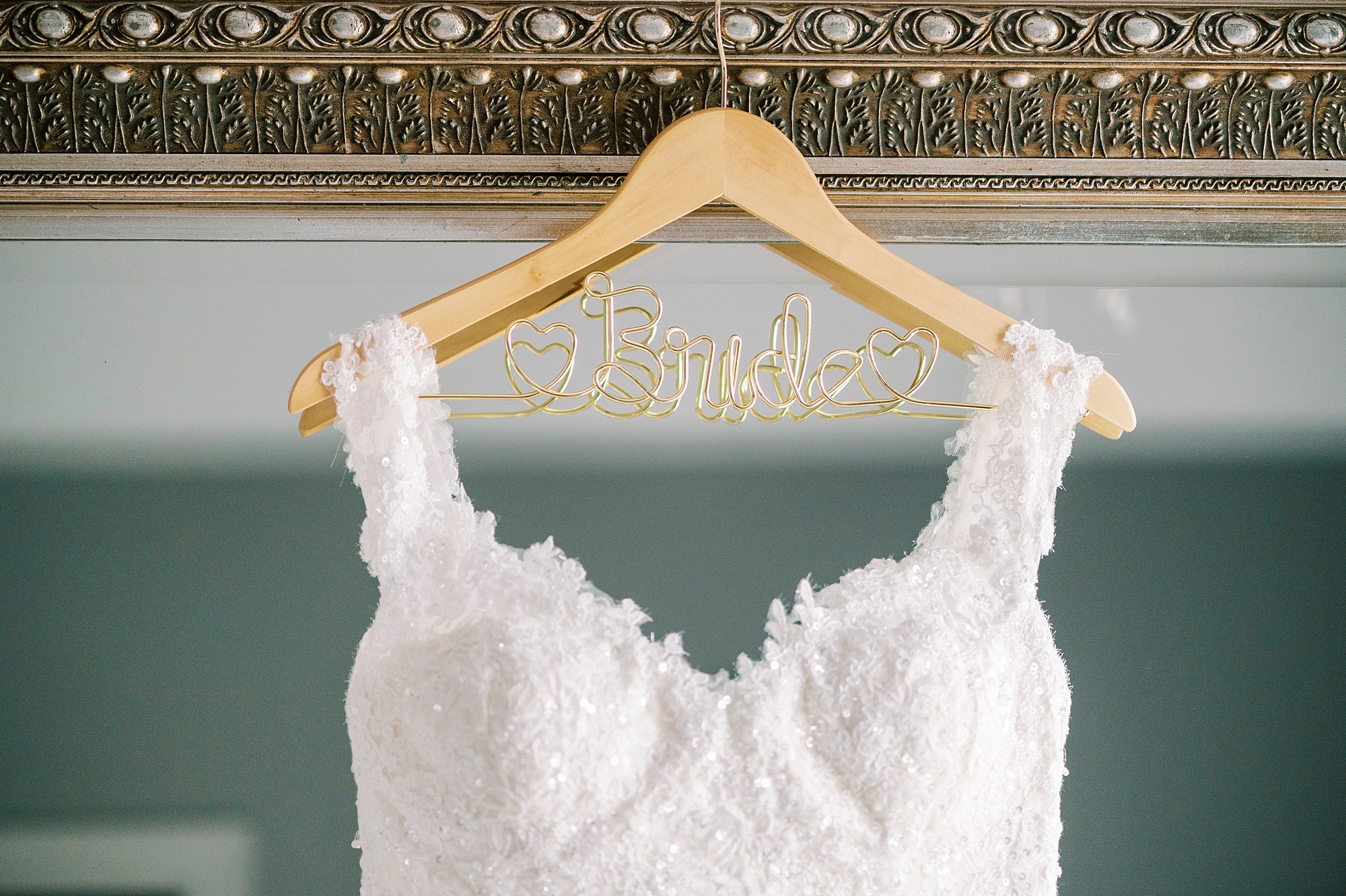 wedding gown hangs on wooden "bride" hanger
