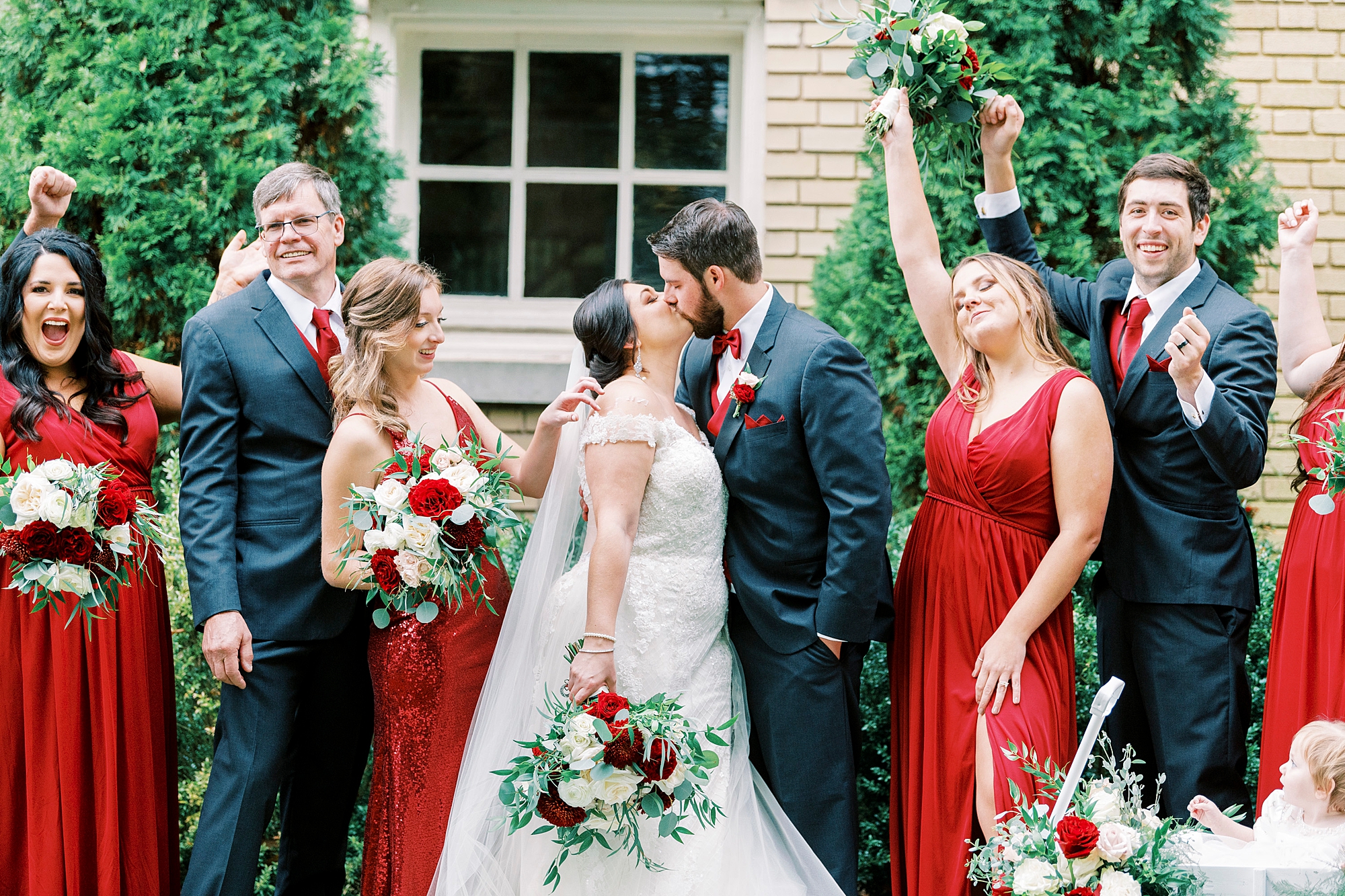 bride and groom kiss by Separk Mansion with wedding party cheering