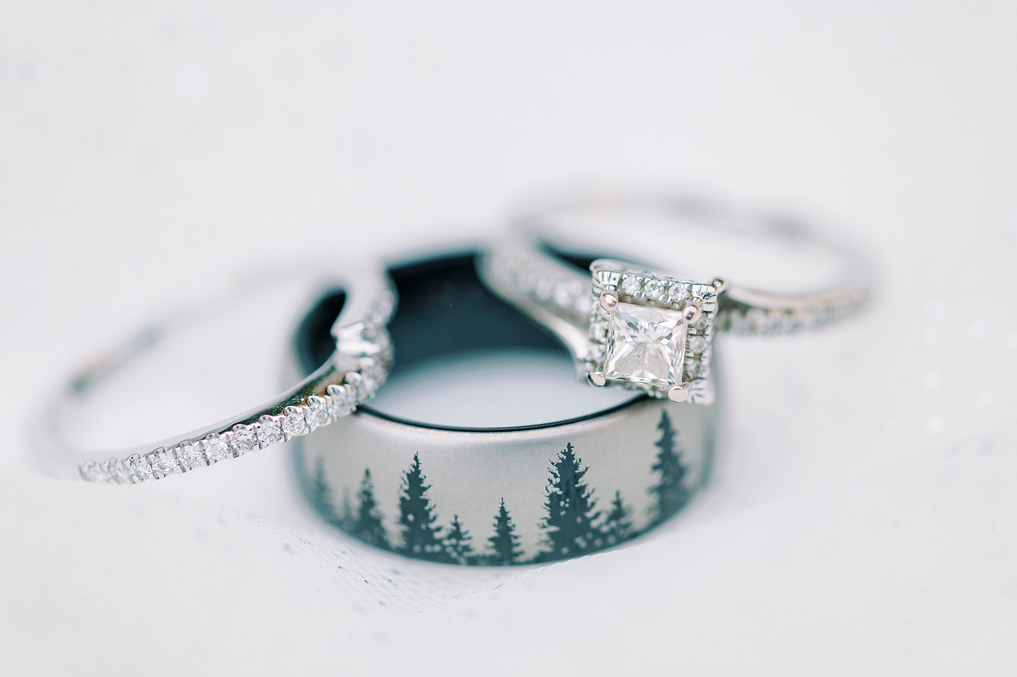 wedding ring with trees engaged rests under diamond ring