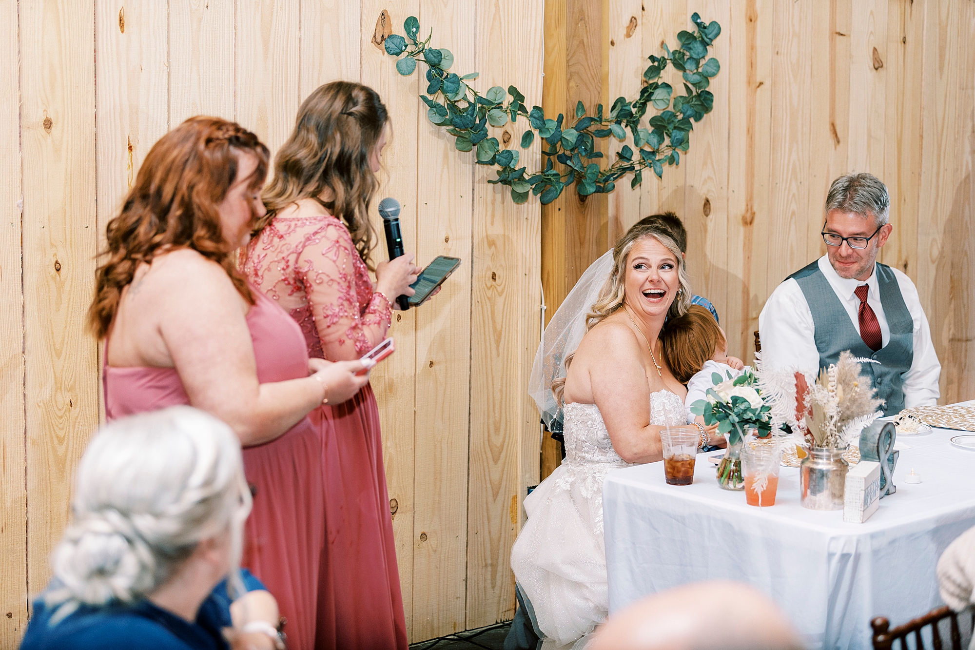 bride listens to daughters in pink gowns read speeches during reception