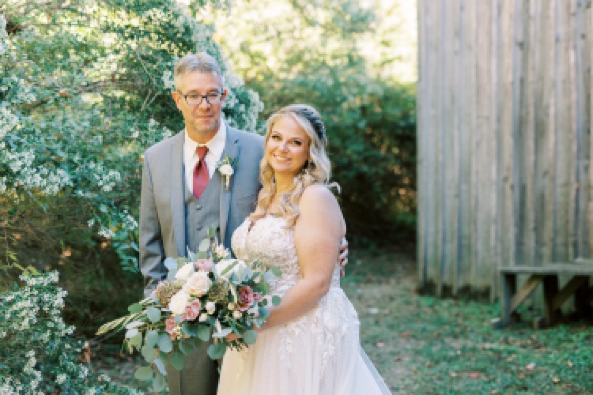 bride and groom smile walking by barn at the Gin at Aw Shucks Farm