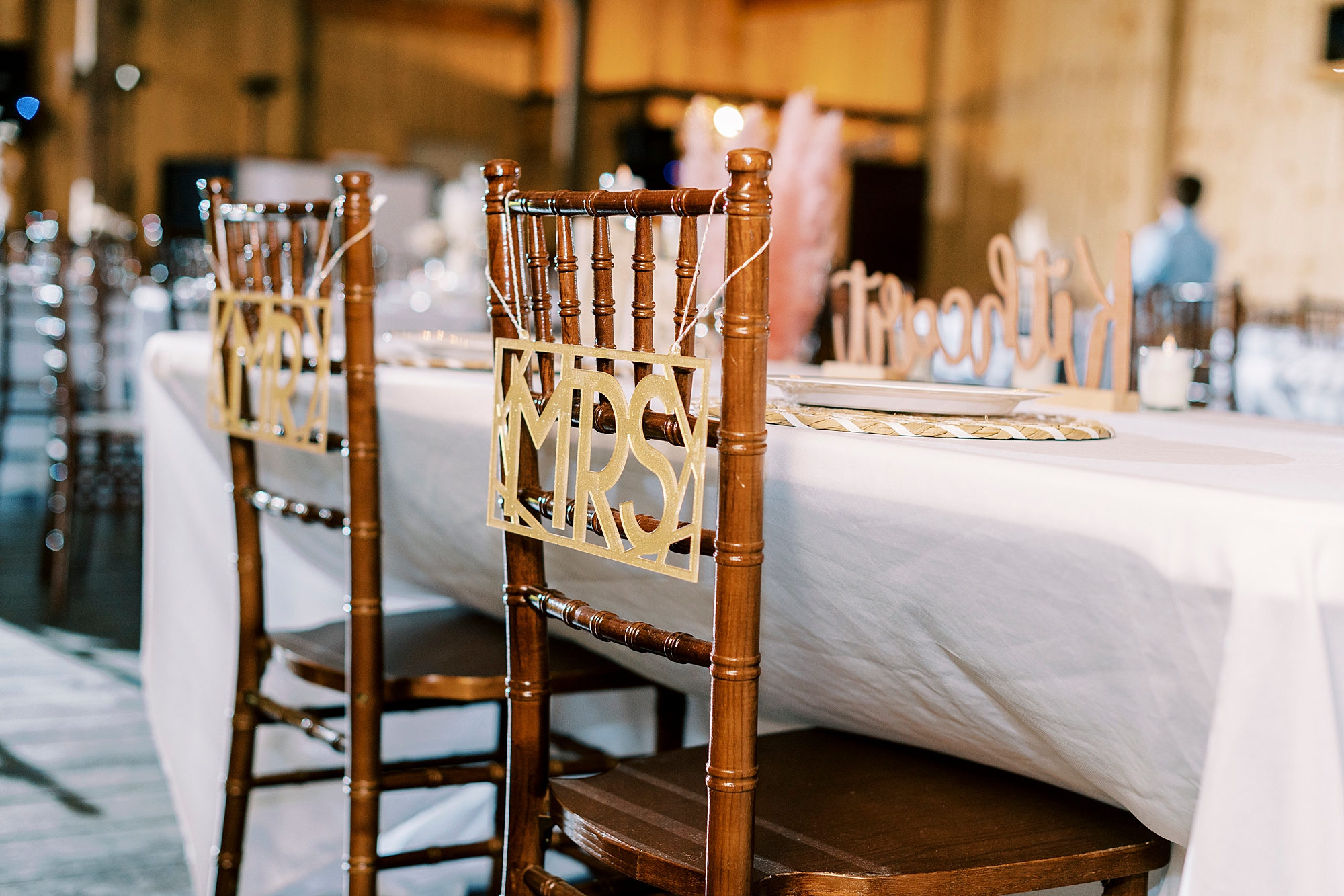 Gold MRS and MR signs on back of wooden chairs at the Gin at Aw Shucks Farm