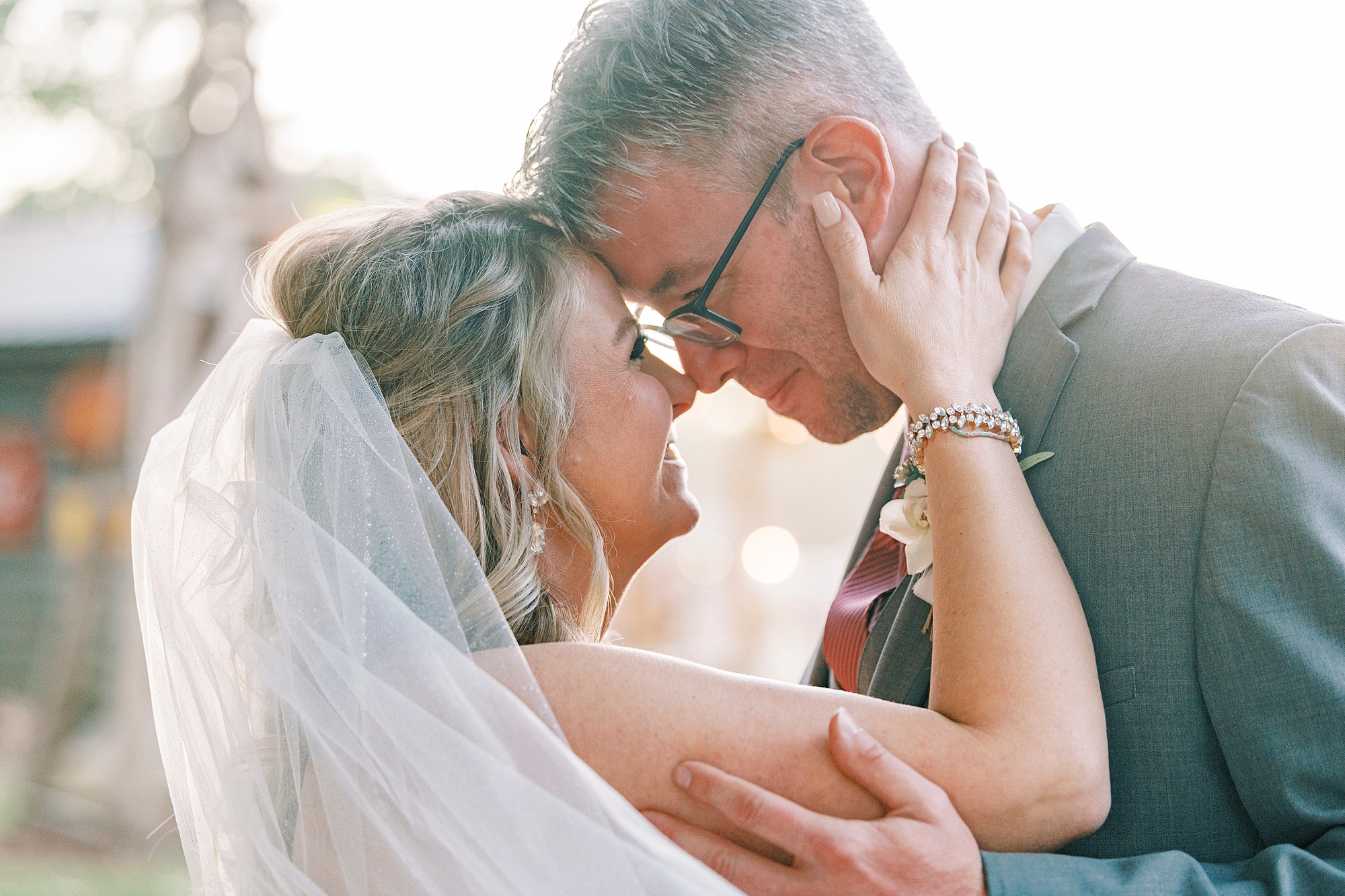 bride holds groom's neck during portraits at the Gin at Aw Shucks Farm