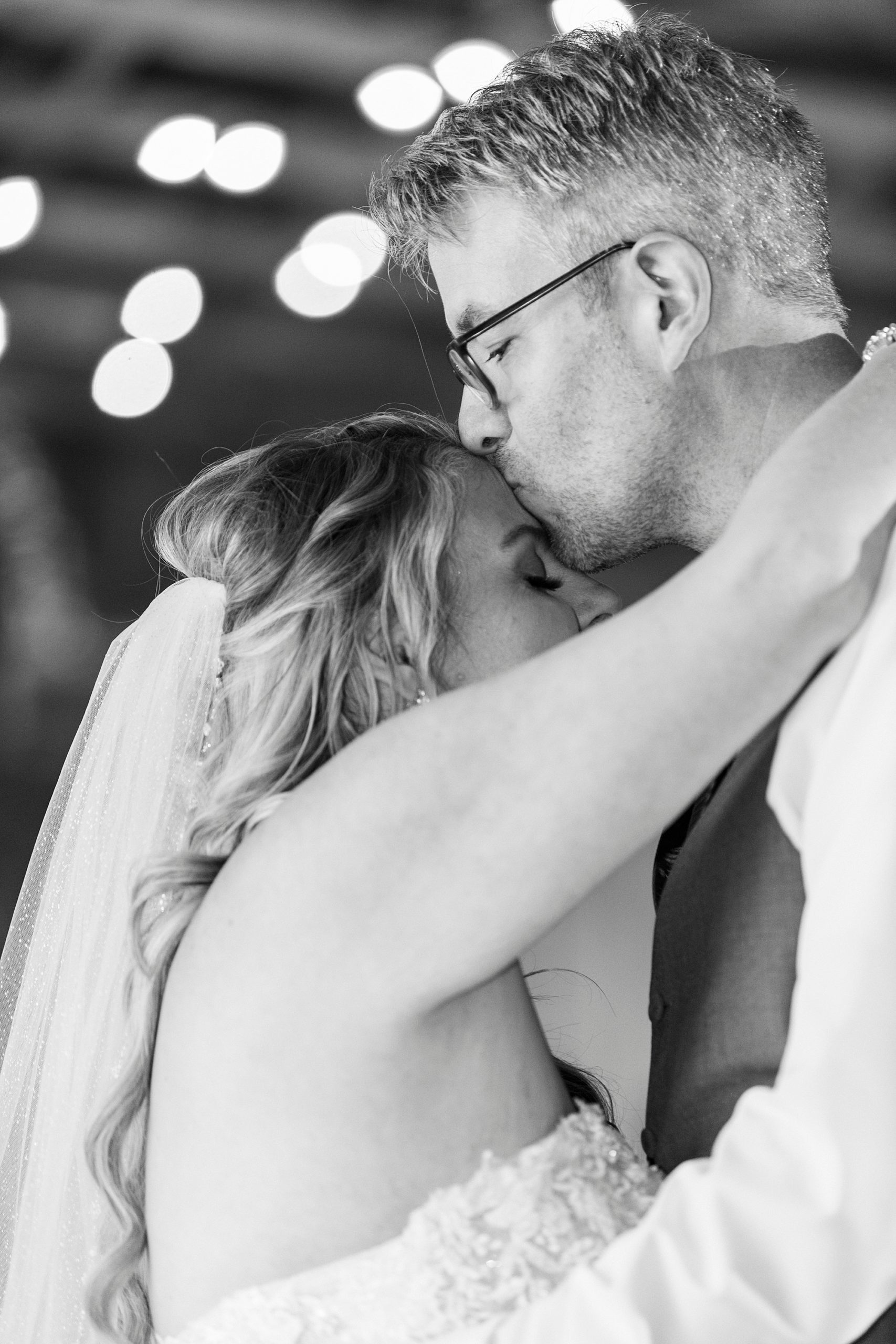 groom kisses bride's forehead during first dance