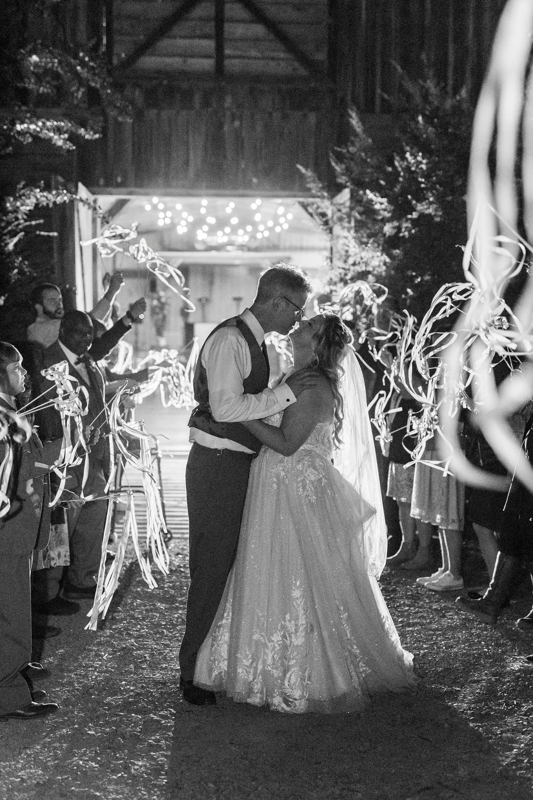 bride and groom kiss during ribbon exit at the Gin at Aw Shucks Farm