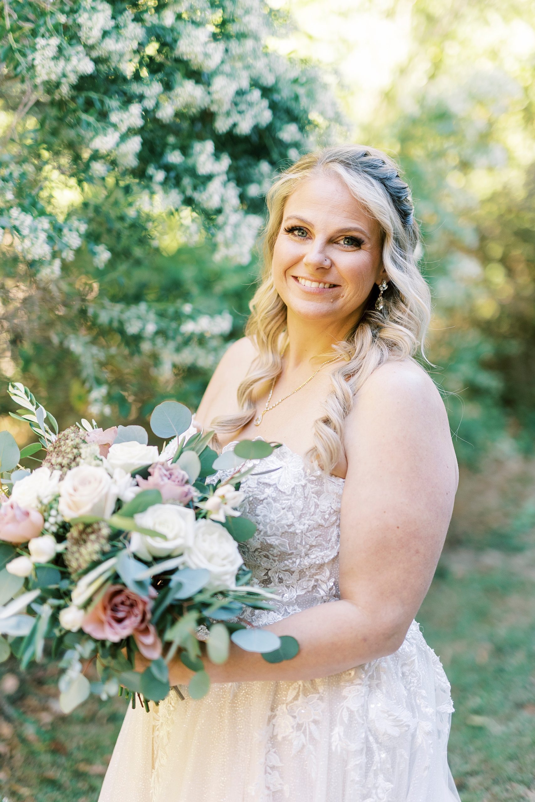 bride smiles holding pink and white floral bouquet at the Gin at Aw Shucks Farm