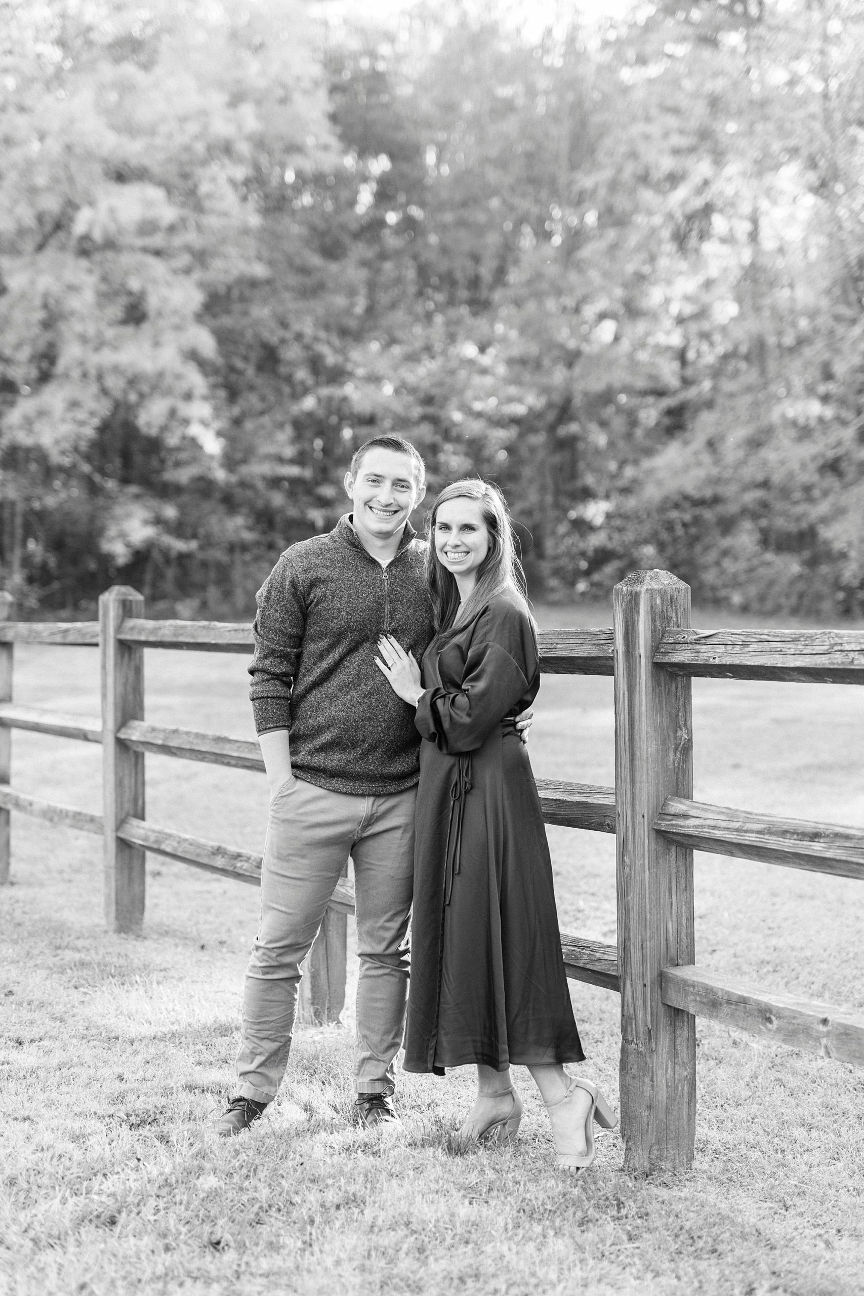 engaged couple hugs alongside wooden fence at Latta Nature Preserve