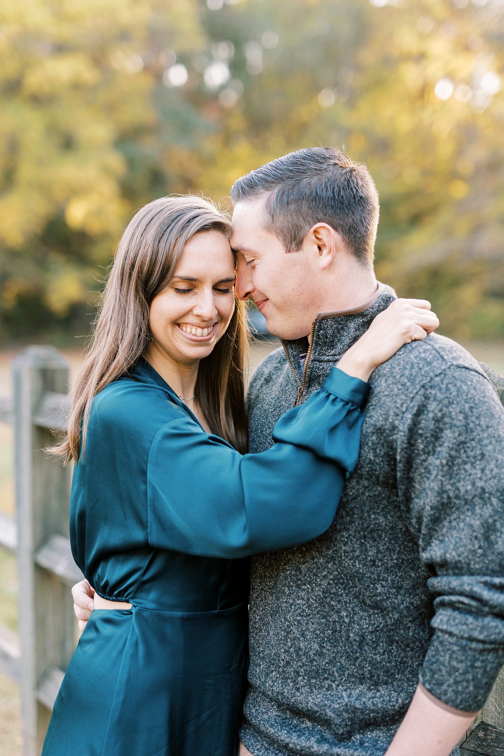 man leans into bride's forehead during fall engagement photos