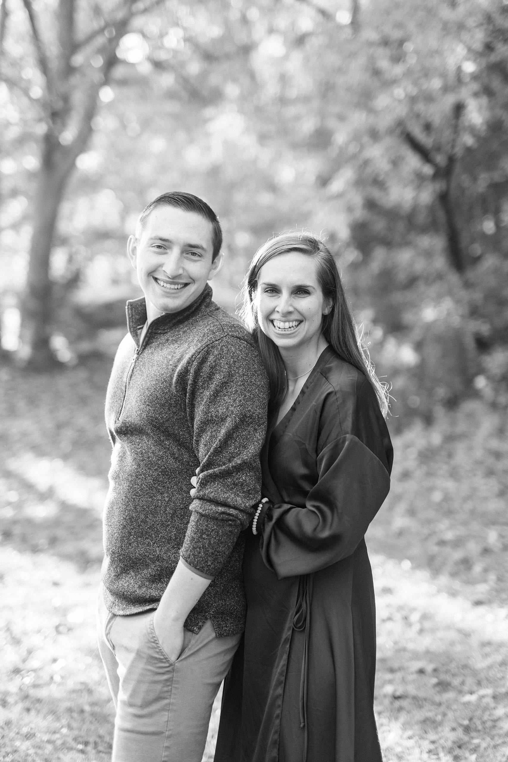 woman hugs fiancee from behind during fall engagement photos