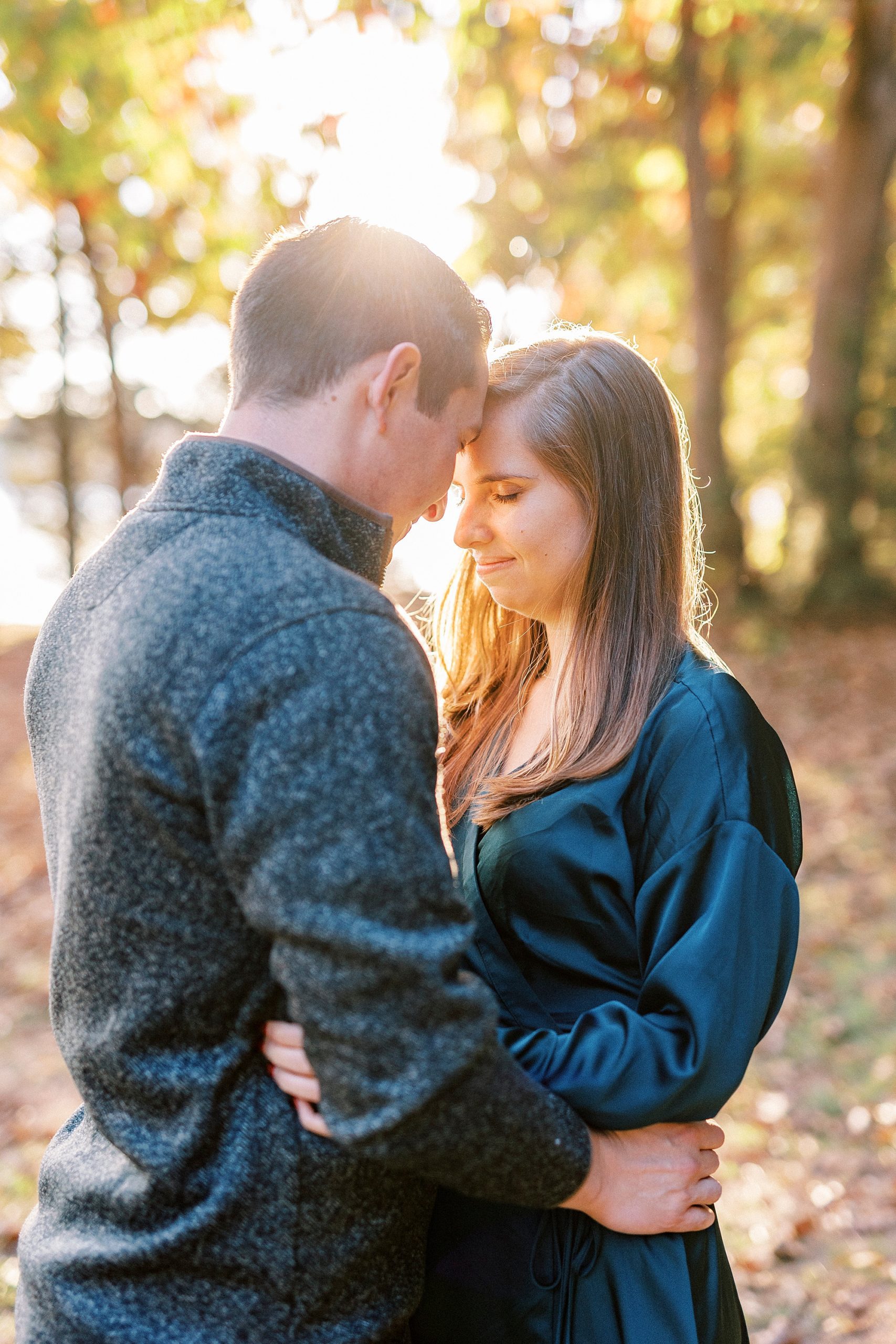 groom leans head to bride's during fall engagement session at sunset at Latta Nature Preserve