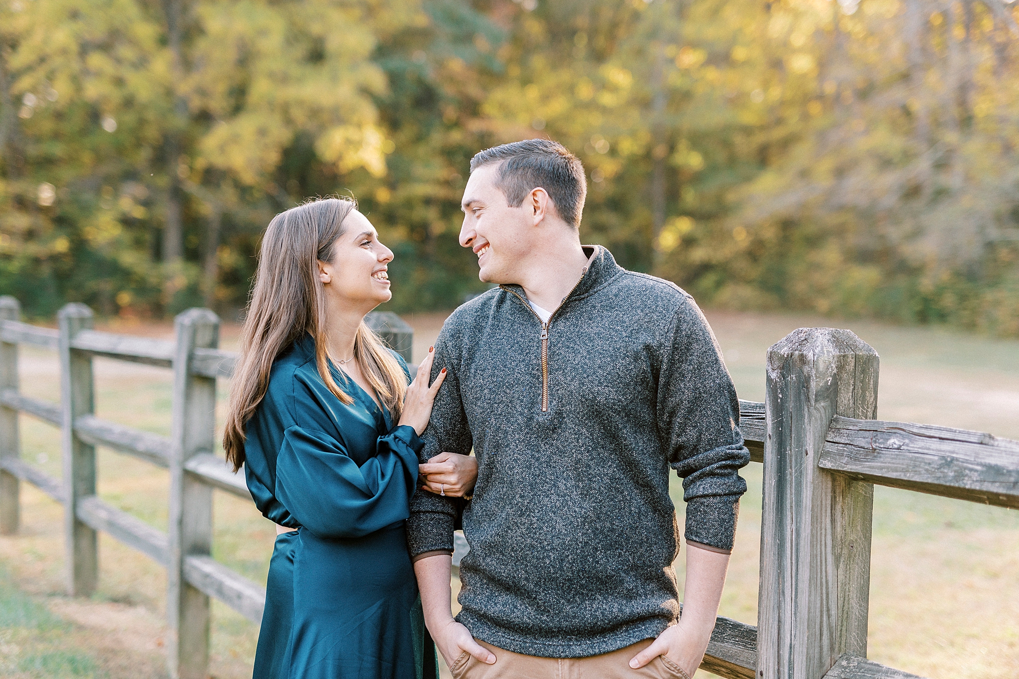engaged couple stands together holding each other along Woden fence at Latta Nature Preserve